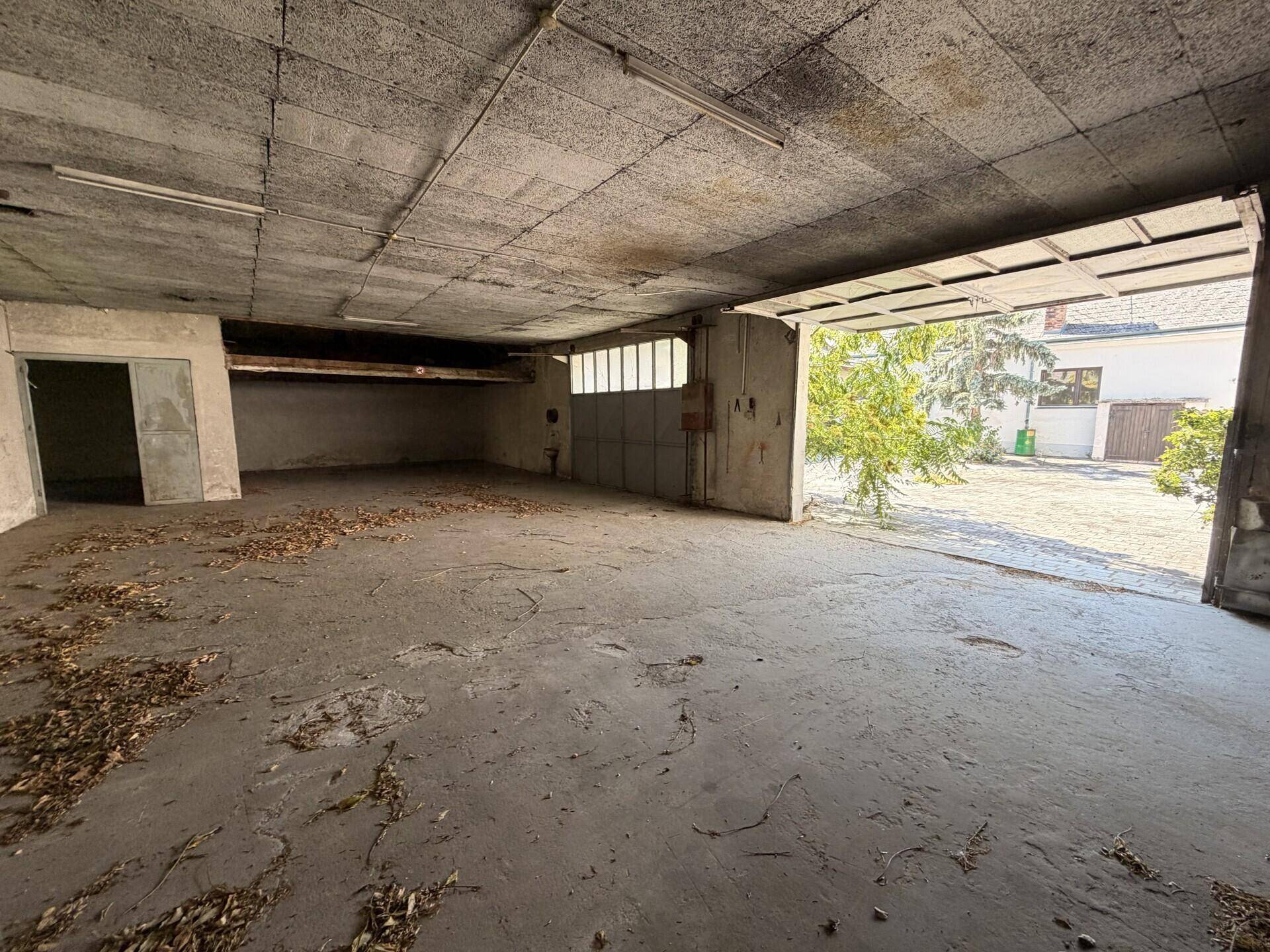 Geräumige, leere Garage mit Betonboden und großem Zugang zum Außenbereich.