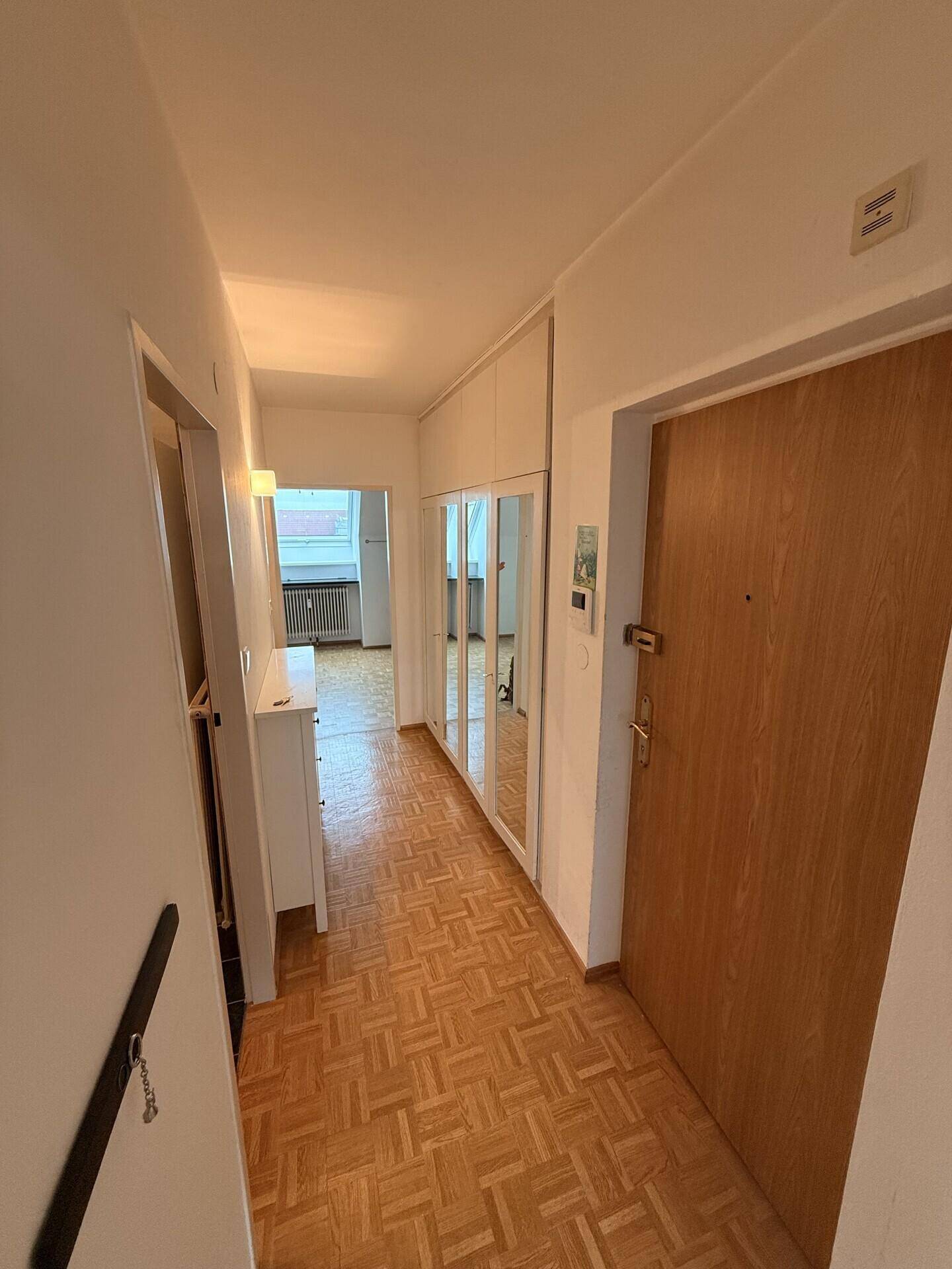 Eingangsbereich mit Holzparkett und integrierten Spiegelschränken, Blick zur Wohnungstür.