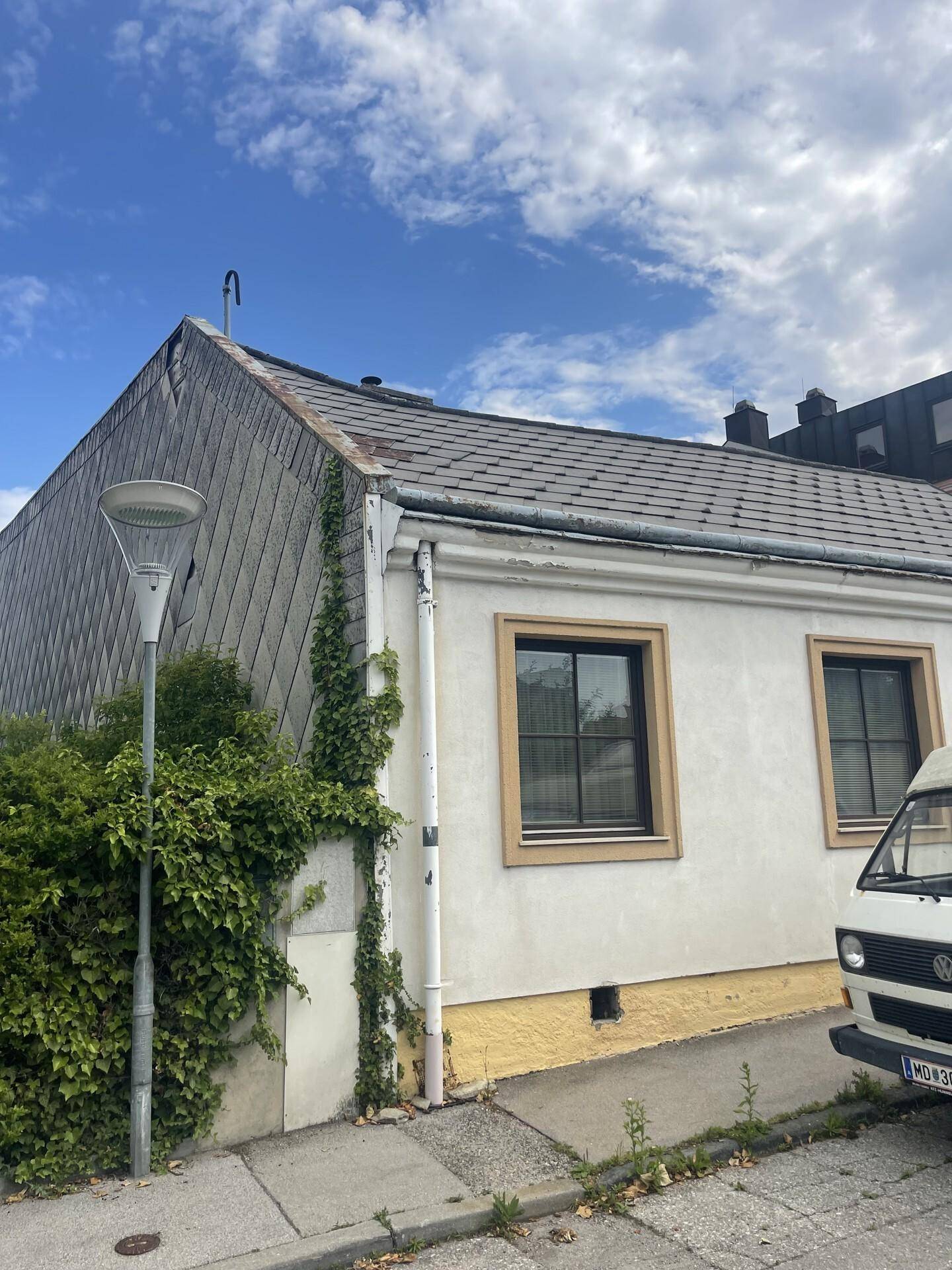 Seitenansicht des Hauses mit Schieferdach und Efeu an der Wand, von der Straße aus.