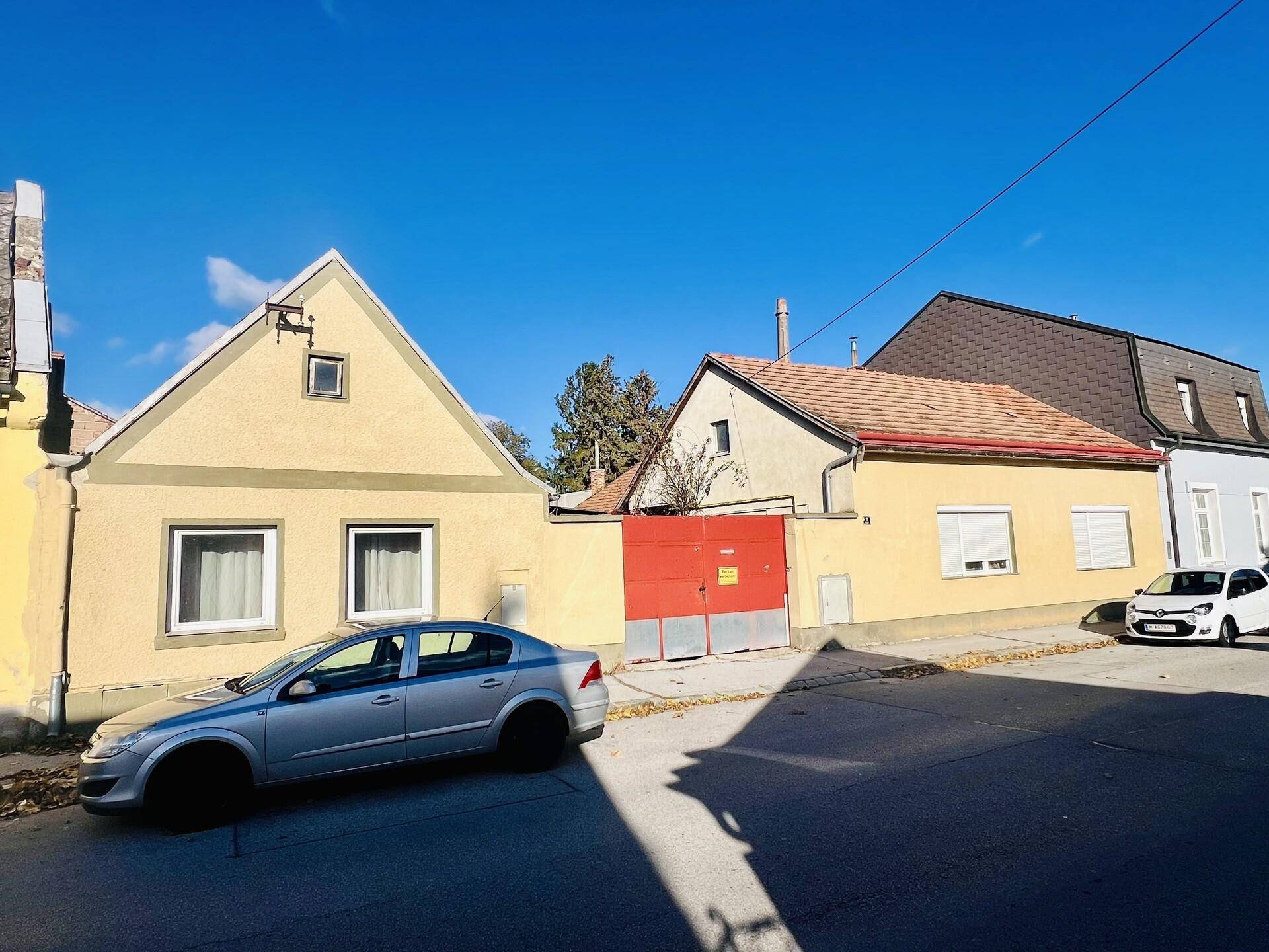 Straßenansicht von traditionellen Häusern mit gelber Fassade und einem roten Tor.