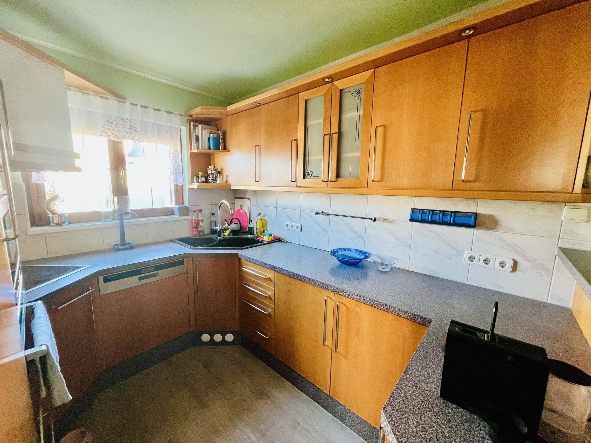 Geräumige Küche mit Holzfronten, Fenster und ausreichend Arbeitsfläche.