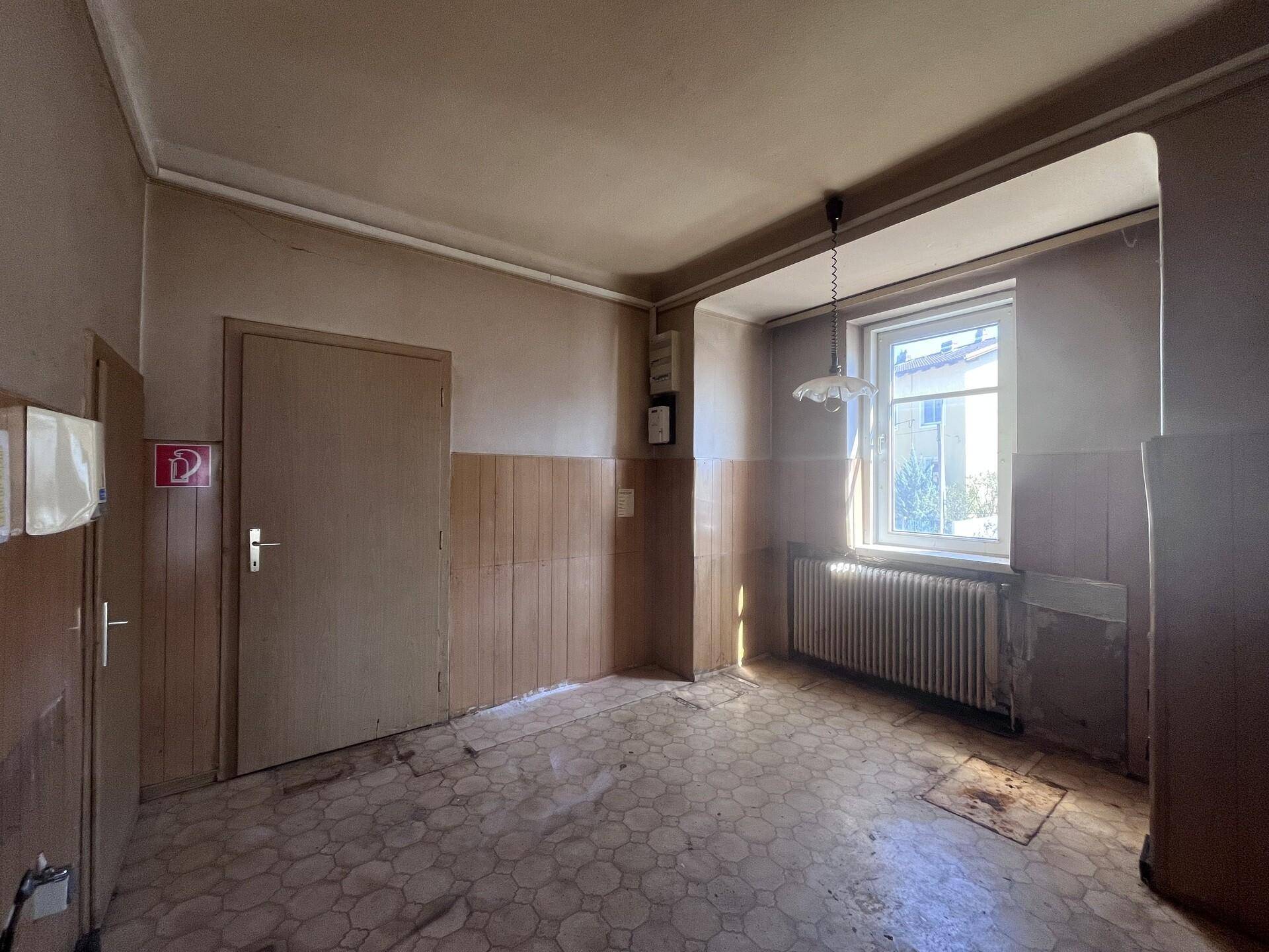 Flur mit gemustertem Boden, Holzvertäfelung und einem Fenster, das Licht hereinlässt.
