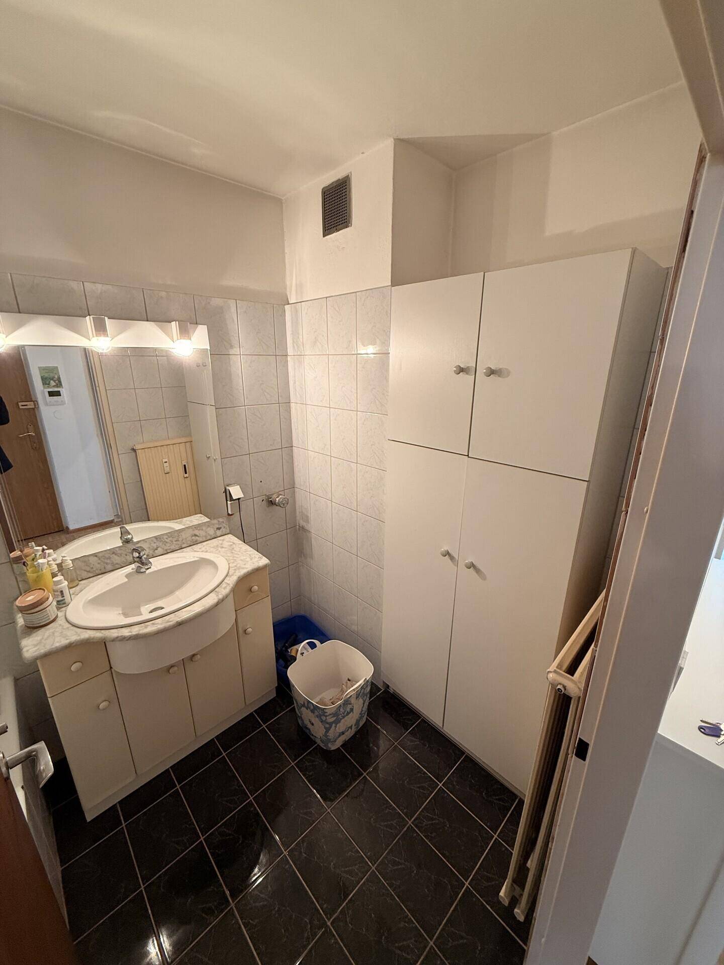 Badezimmer mit Waschbecken, Spiegelschrank und praktischen Einbauschränken.