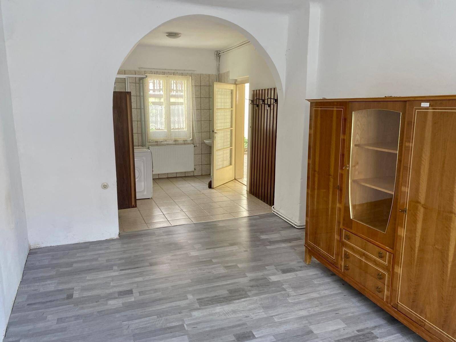 Heller Raum mit modernem Laminatboden, Rundbogen und einem Schrank im Landhausstil.