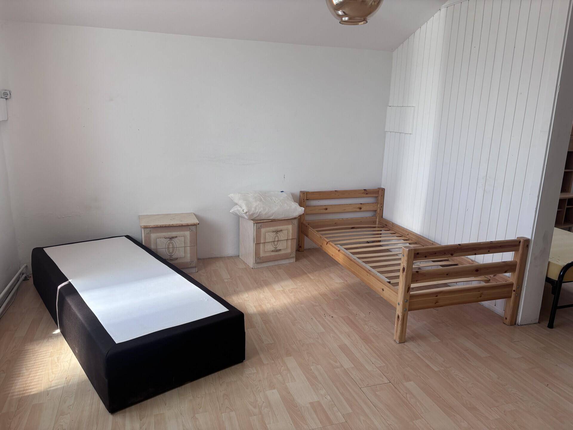 Schlafzimmer mit zwei Betten, Nachttischen und hellem Laminatboden in einem einfachen Stil.