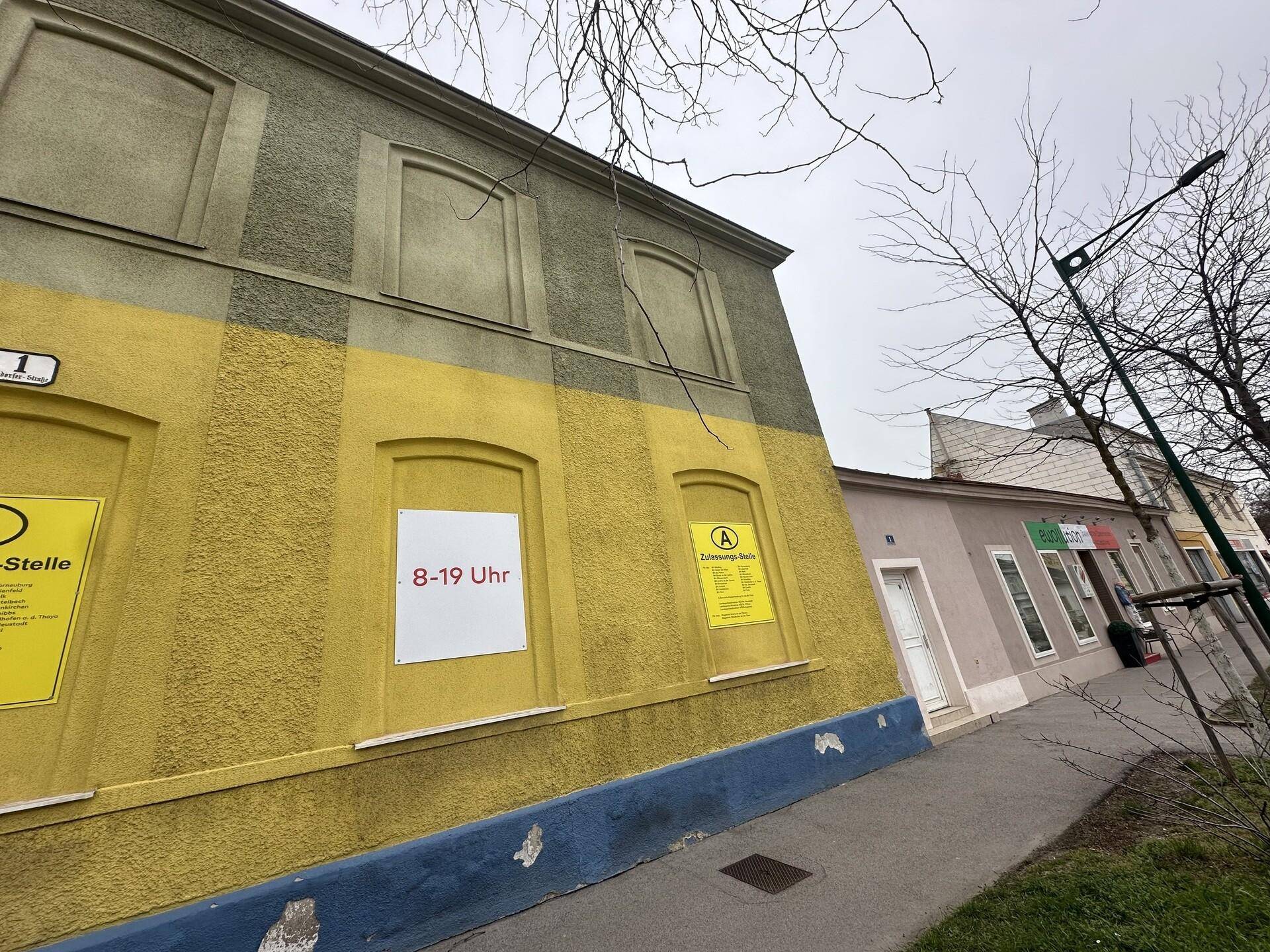 Nahaufnahme der Fassade mit gelbem Erdgeschoss und grüner Obergeschossgestaltung.