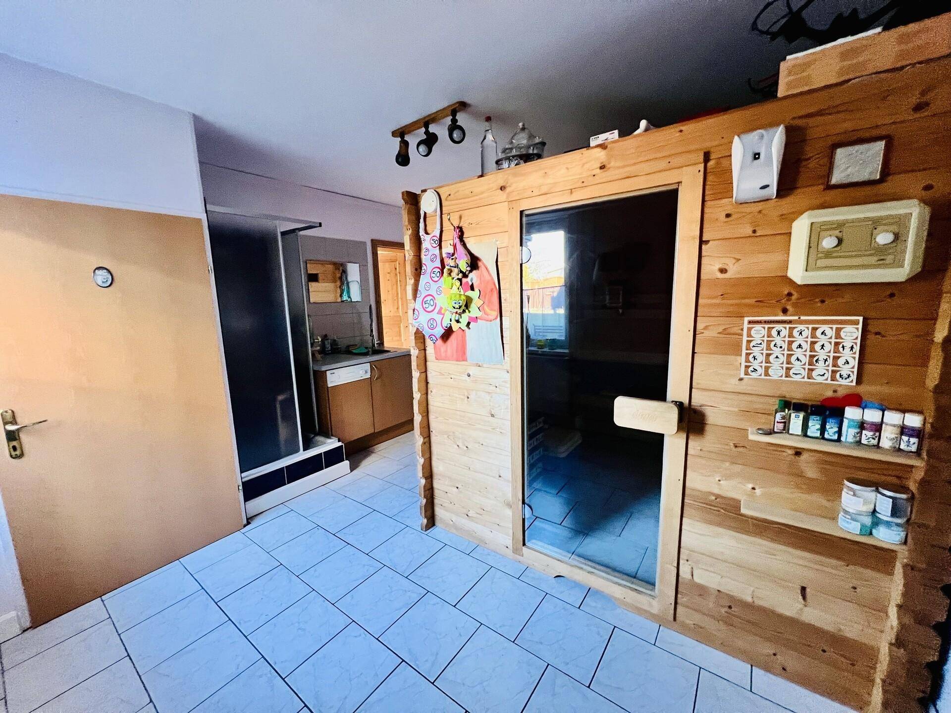 Saunakabine aus Holz mit angrenzendem Duschbereich und gefliestem Boden.