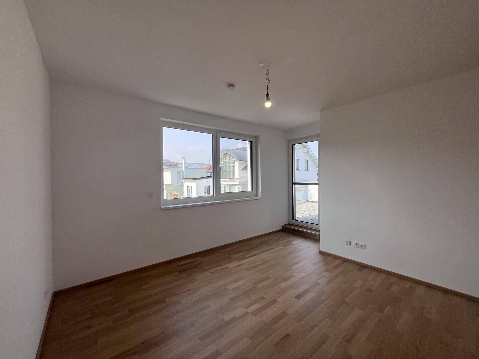 Geräumiges Schlafzimmer mit Parkettboden und Zugang zu einem Balkon.