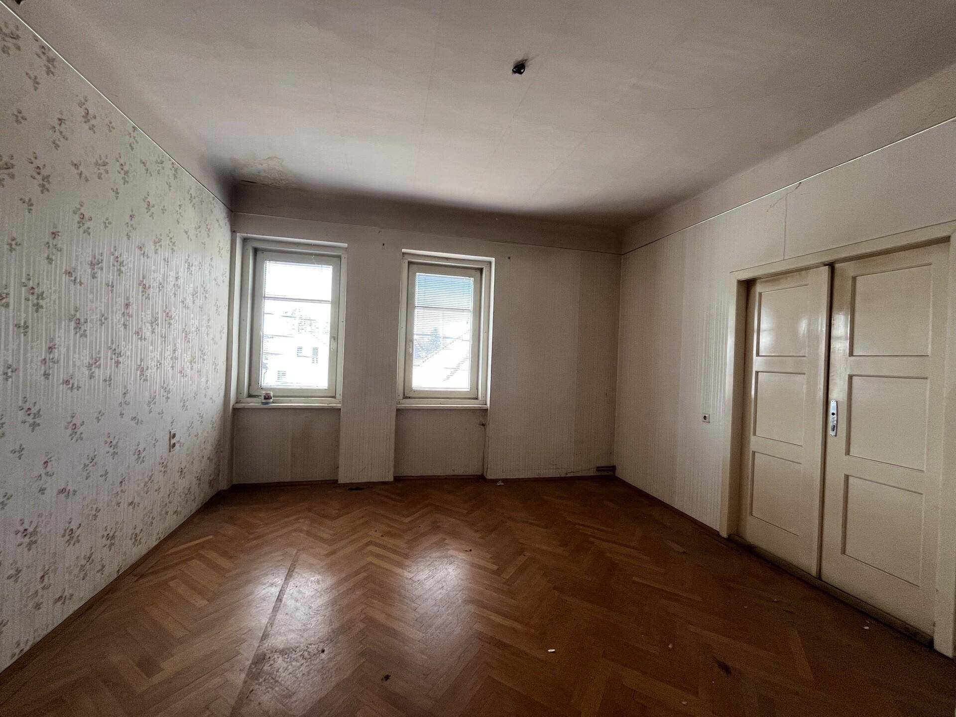 Geräumiges Zimmer mit Fischgrätparkett und Doppeltüren, bereit zur individuellen Gestaltung.