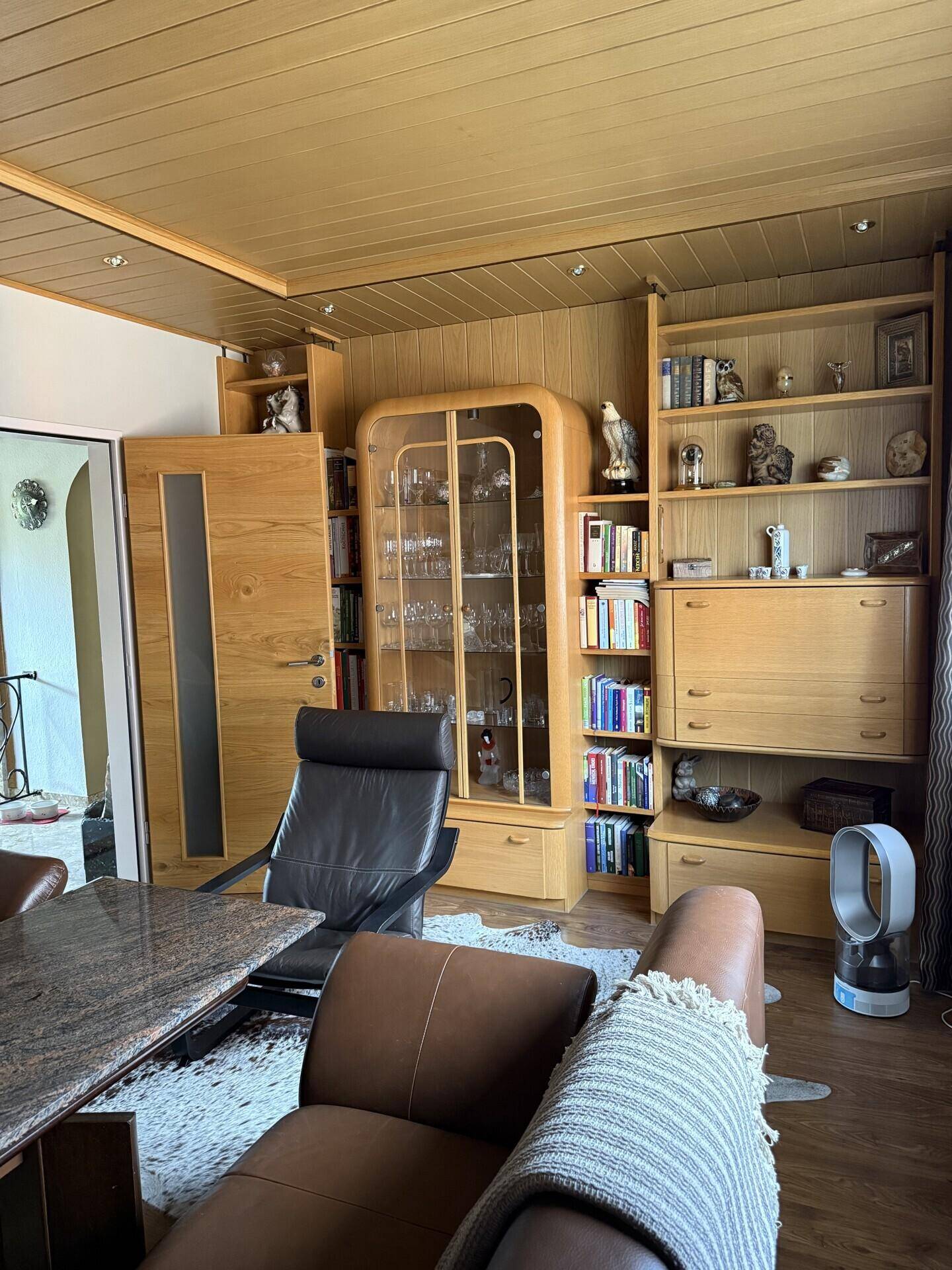 Wohnbereich mit Holzvertäfelung, Bücherregalen und bequemen Ledersesseln.