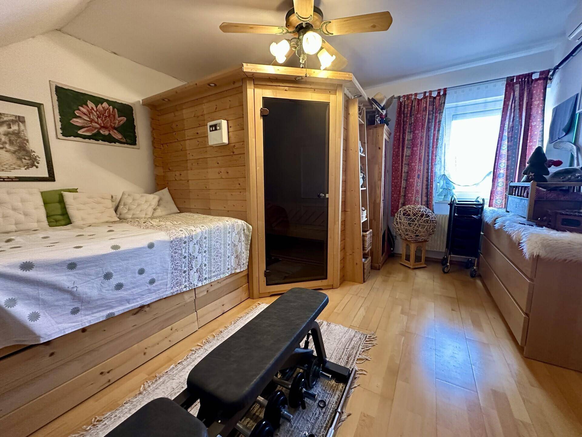 Schlafzimmer mit Holzboden, integrierter Sauna und Fitnessbereich.