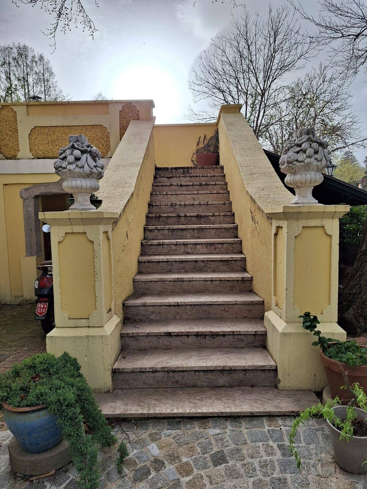 Steintreppe im Außenbereich mit dekorativen Vasen und sonnigem Himmel.