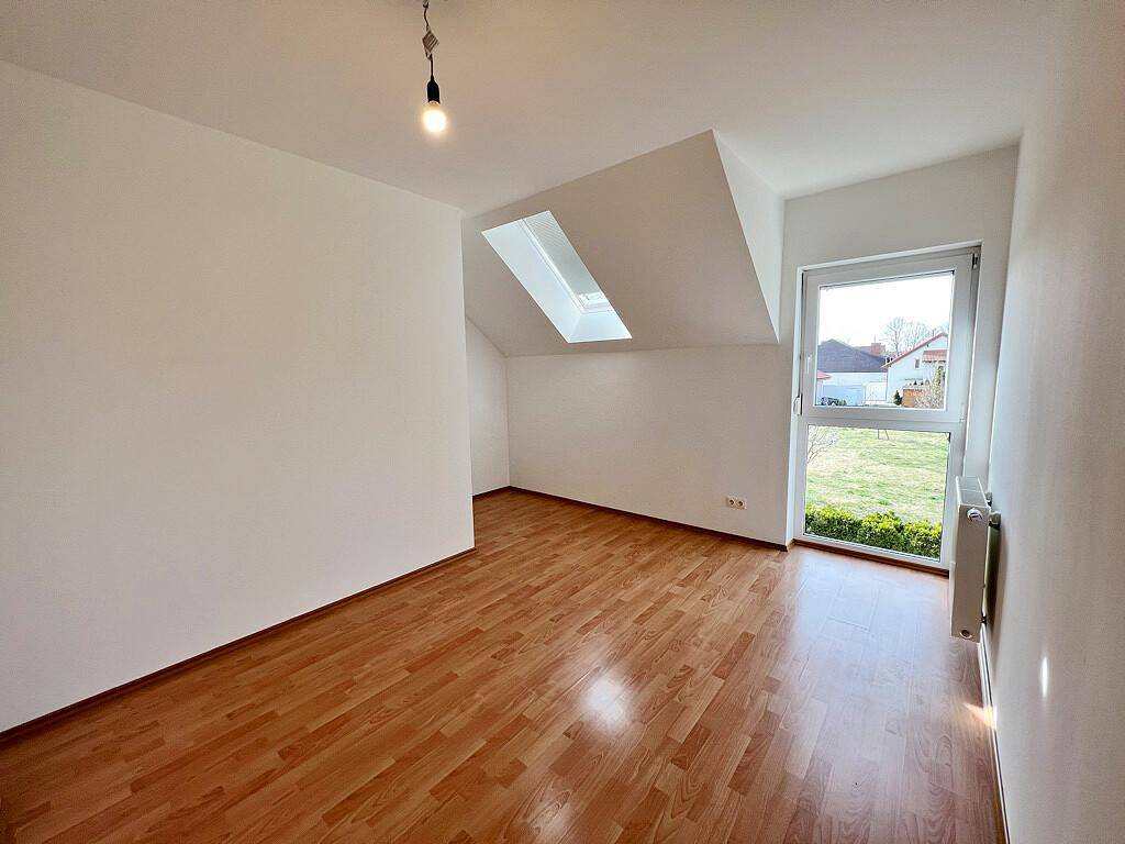 Helles Schlafzimmer mit Laminatboden, Fenster und Dachfenster, sorgt für angenehme Lichtverhältnisse.