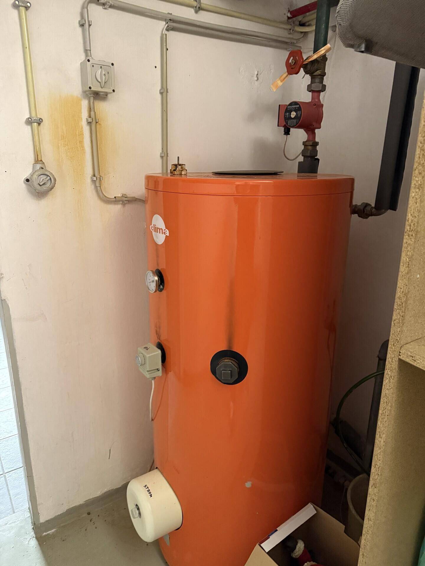 Warmwasserspeicher in einem Technikraum mit Rohrleitungen, sorgt für warmes Wasser.