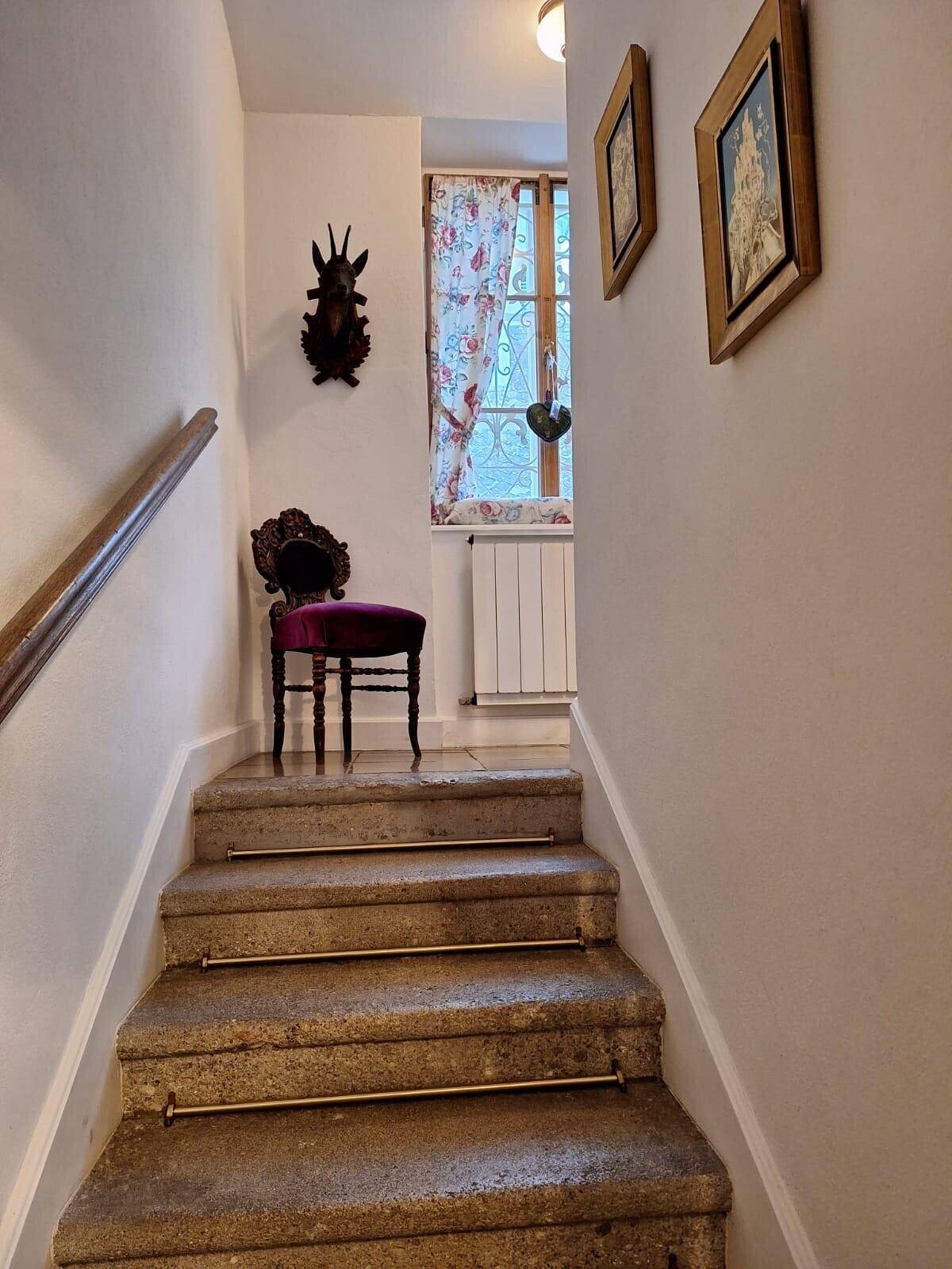 Heller Treppenaufgang mit Steinstufen, kleinem Fenster und traditioneller Dekoration.