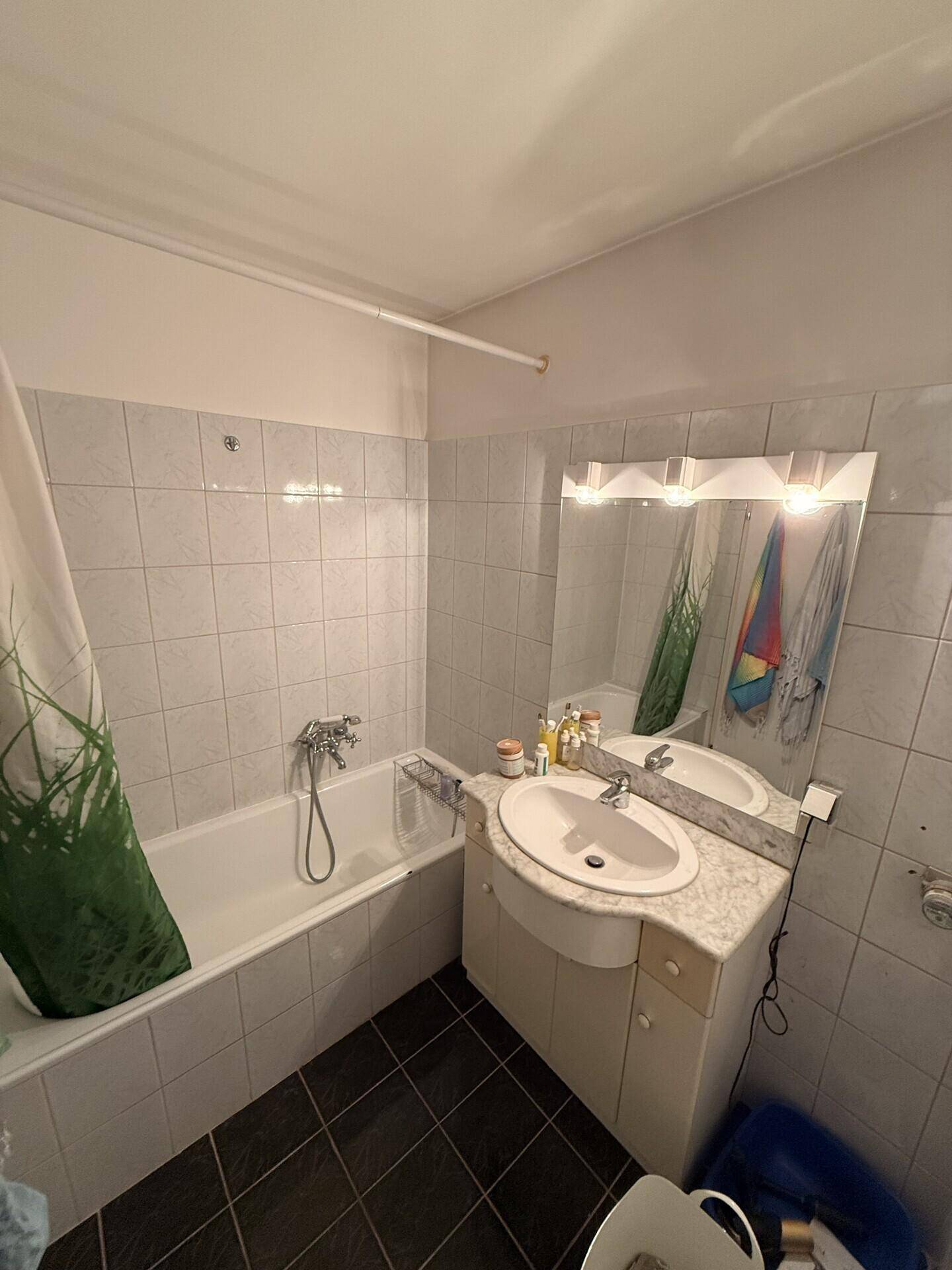 Badezimmer mit Badewanne, Waschbecken und Spiegelschrank, gefliest.