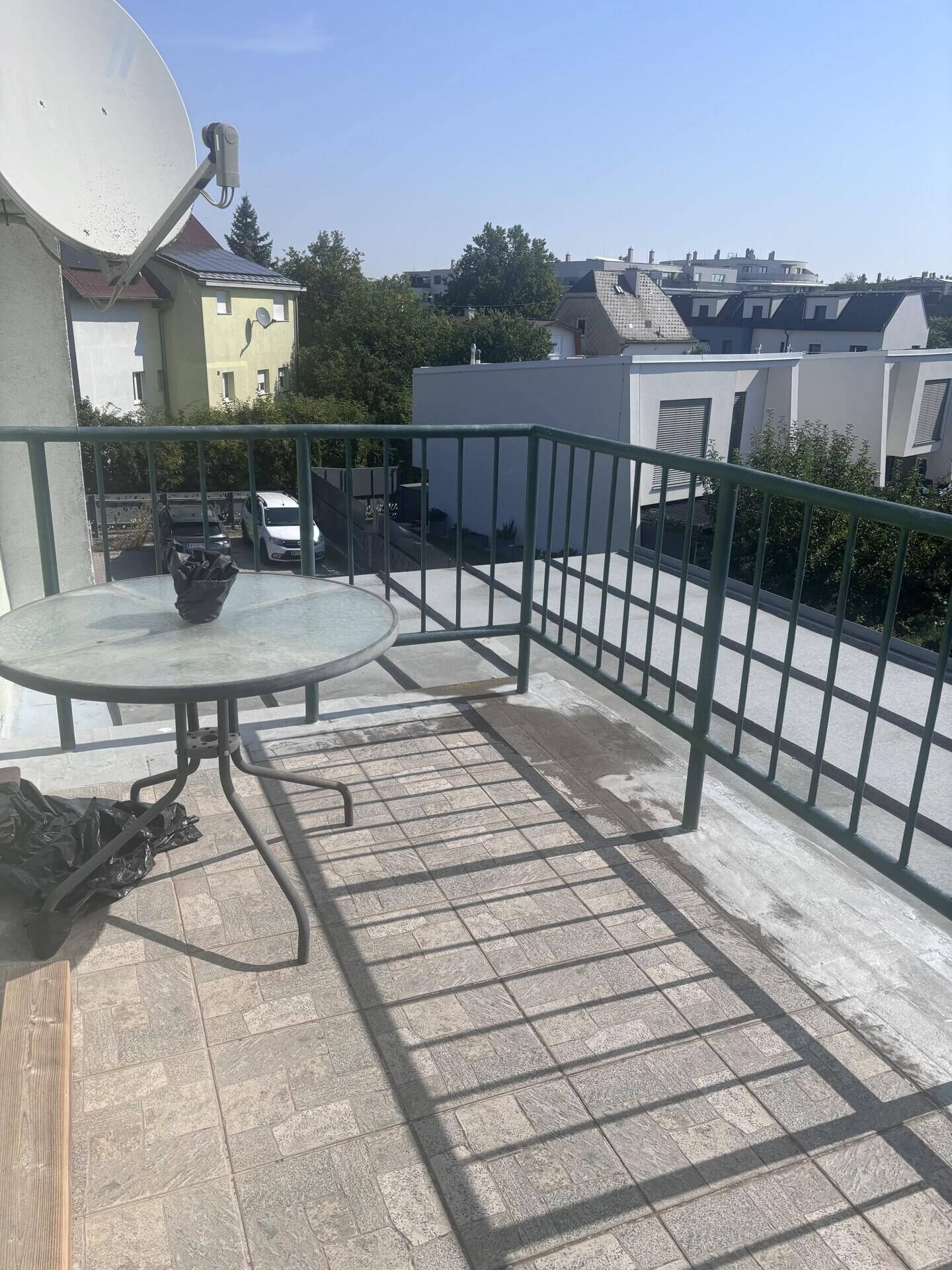 Kleiner Balkon mit Fliesenboden und einem runden Tisch, bietet einen Blick auf die umliegende Bebauung.