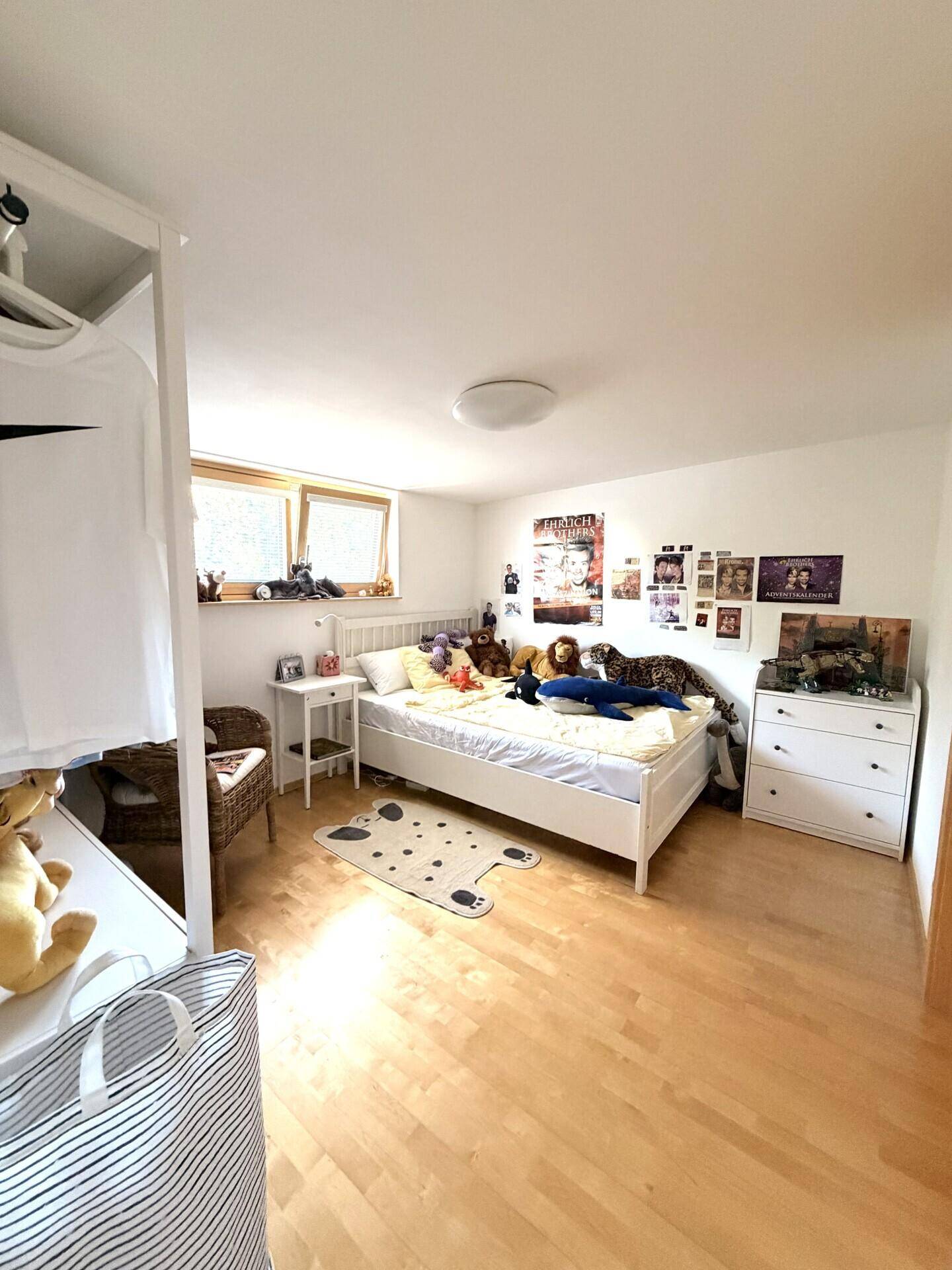 Kinderzimmer mit Holzboden, Einzelbett und vielen Stofftieren, hell und freundlich.