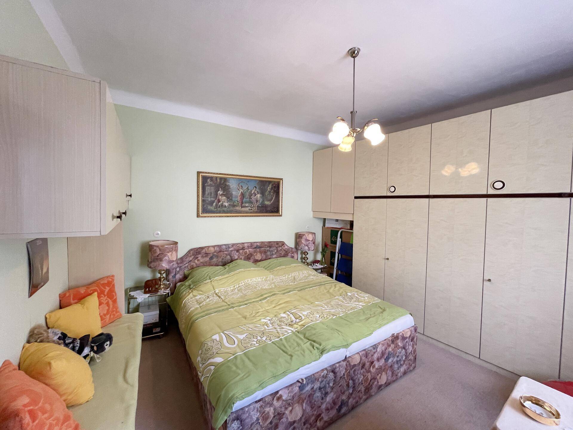 Schlafzimmer mit Doppelbett, Einbauschränken und hellgrünen Wänden.