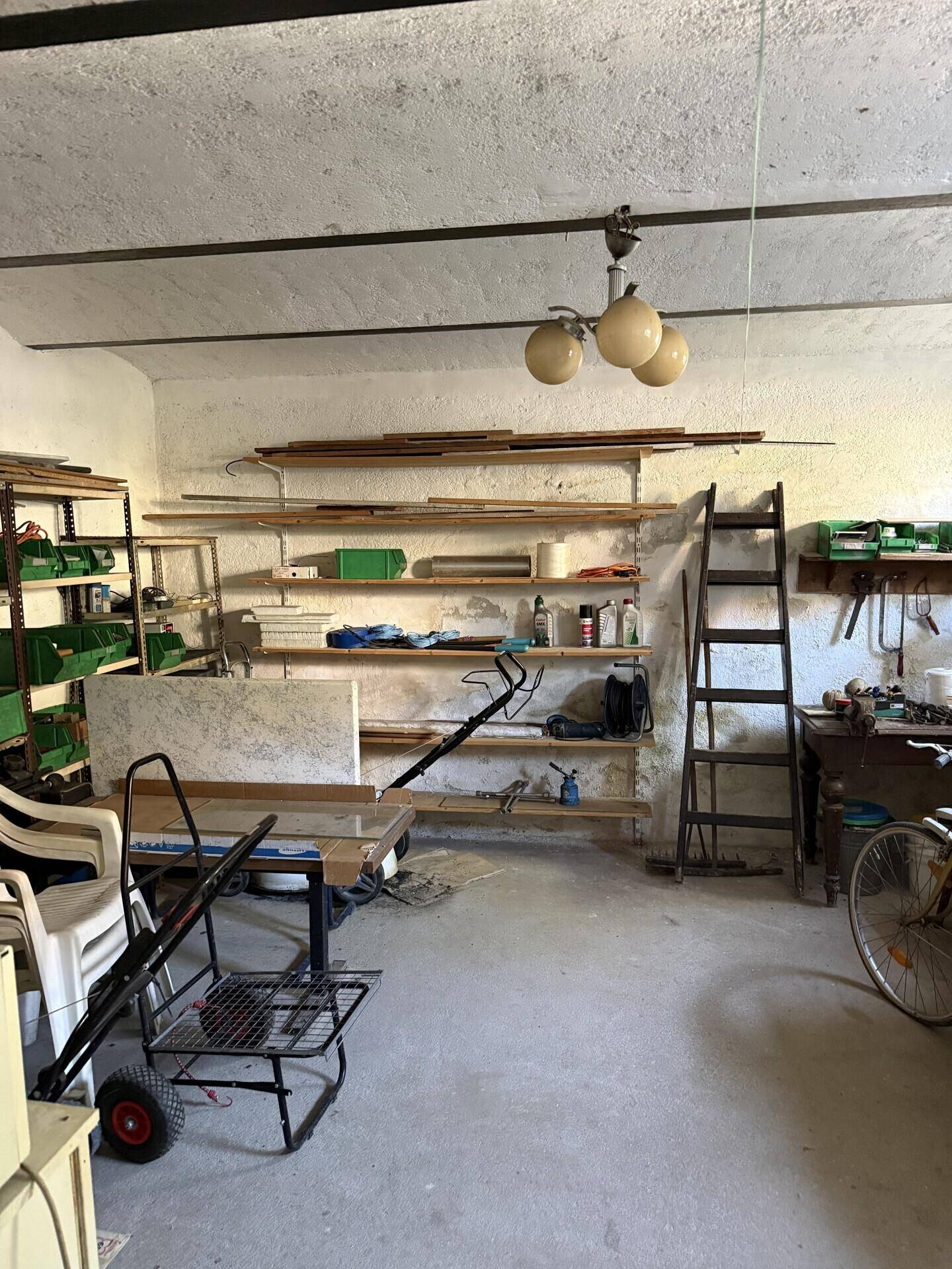 Geräumiger Werkstatt- oder Abstellraum im Keller mit Regalen und Arbeitsbereich.