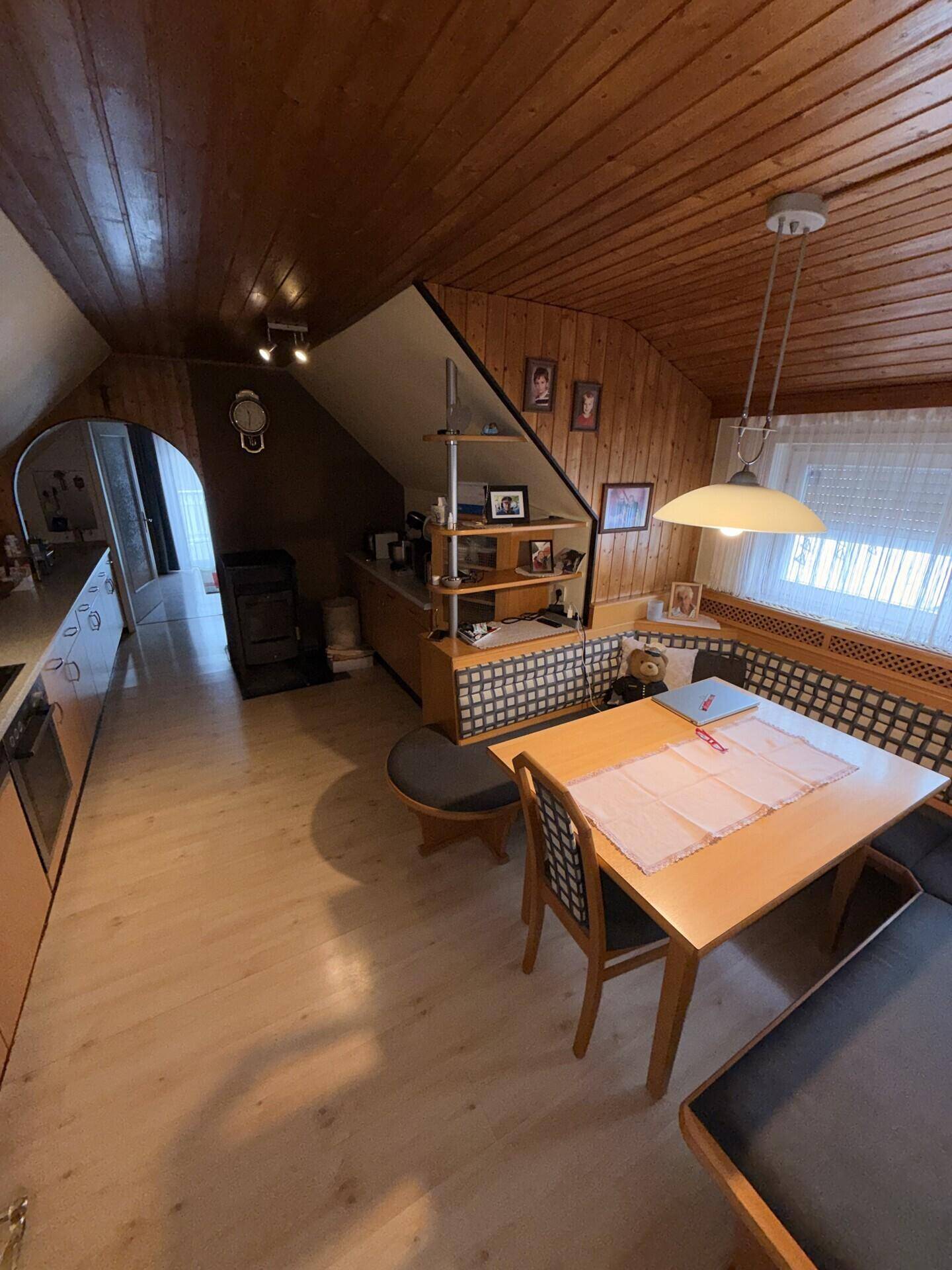 Dachgeschosszimmer mit Dachschrägen, Holzverkleidung und Essbereich in gemütlichem Stil.