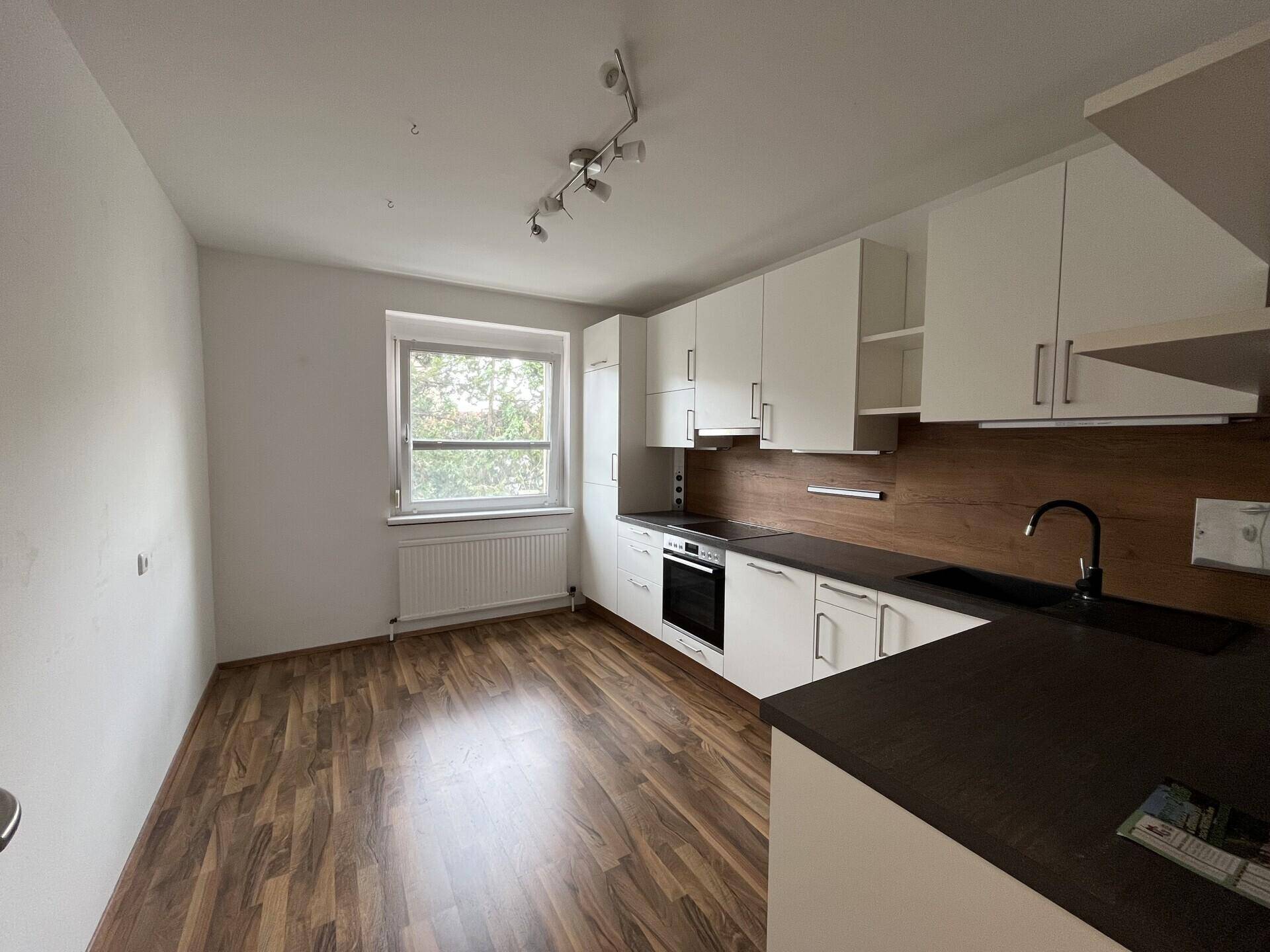 Geräumige Küche mit neuer Einbauküche, Laminatboden und Fenster.