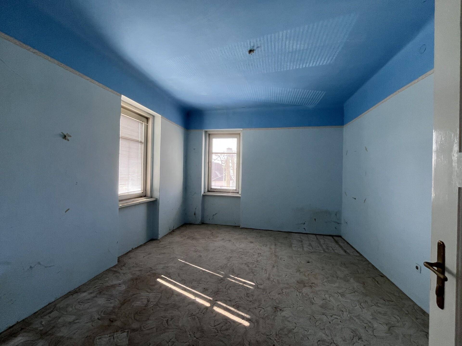 Zimmer mit blauen Wänden und Decke, einem Fenster und einfacher Ausstattung.