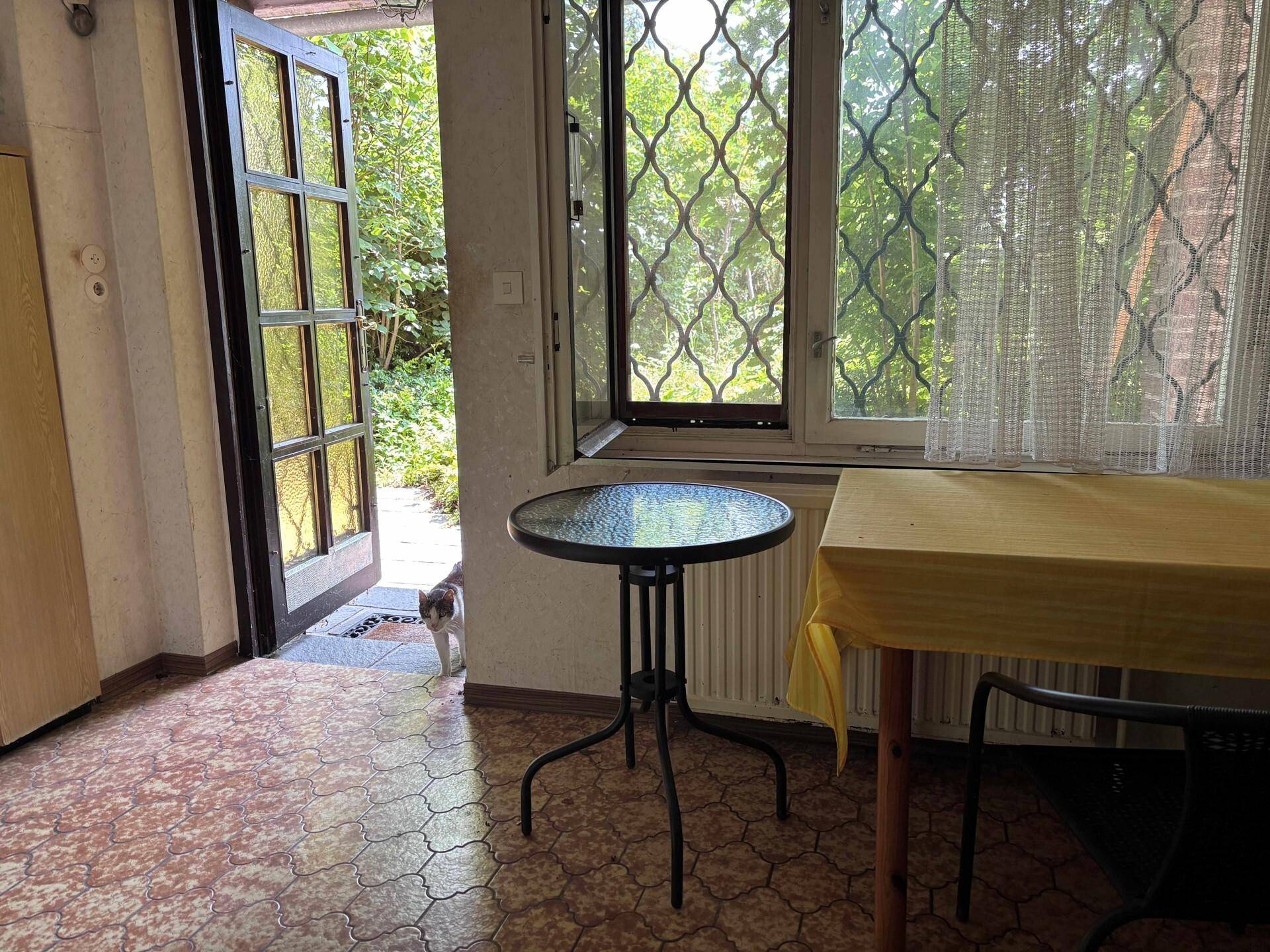 Kleiner Essbereich mit Tisch, Stühlen und Blick ins Grüne durch das Fenster.