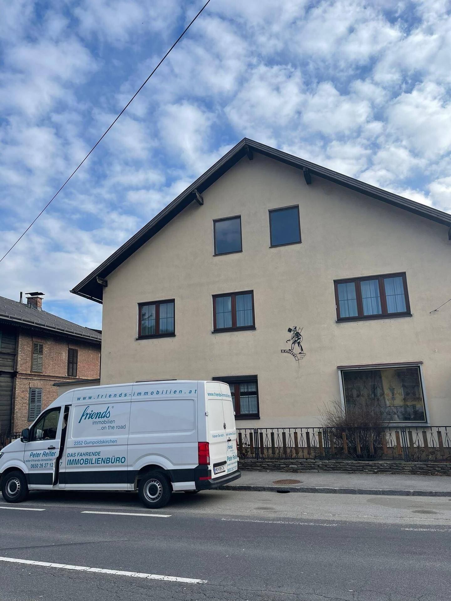 Wohnhausfassade mit Satteldach und braunen Fenstern, von der Straße aus gesehen.