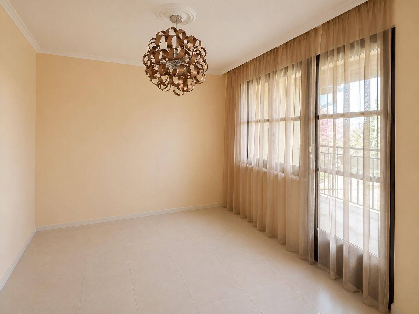 Heller Raum mit beigen Fliesen, einem großen Fenster mit Vorhängen und einer modernen Deckenleuchte.