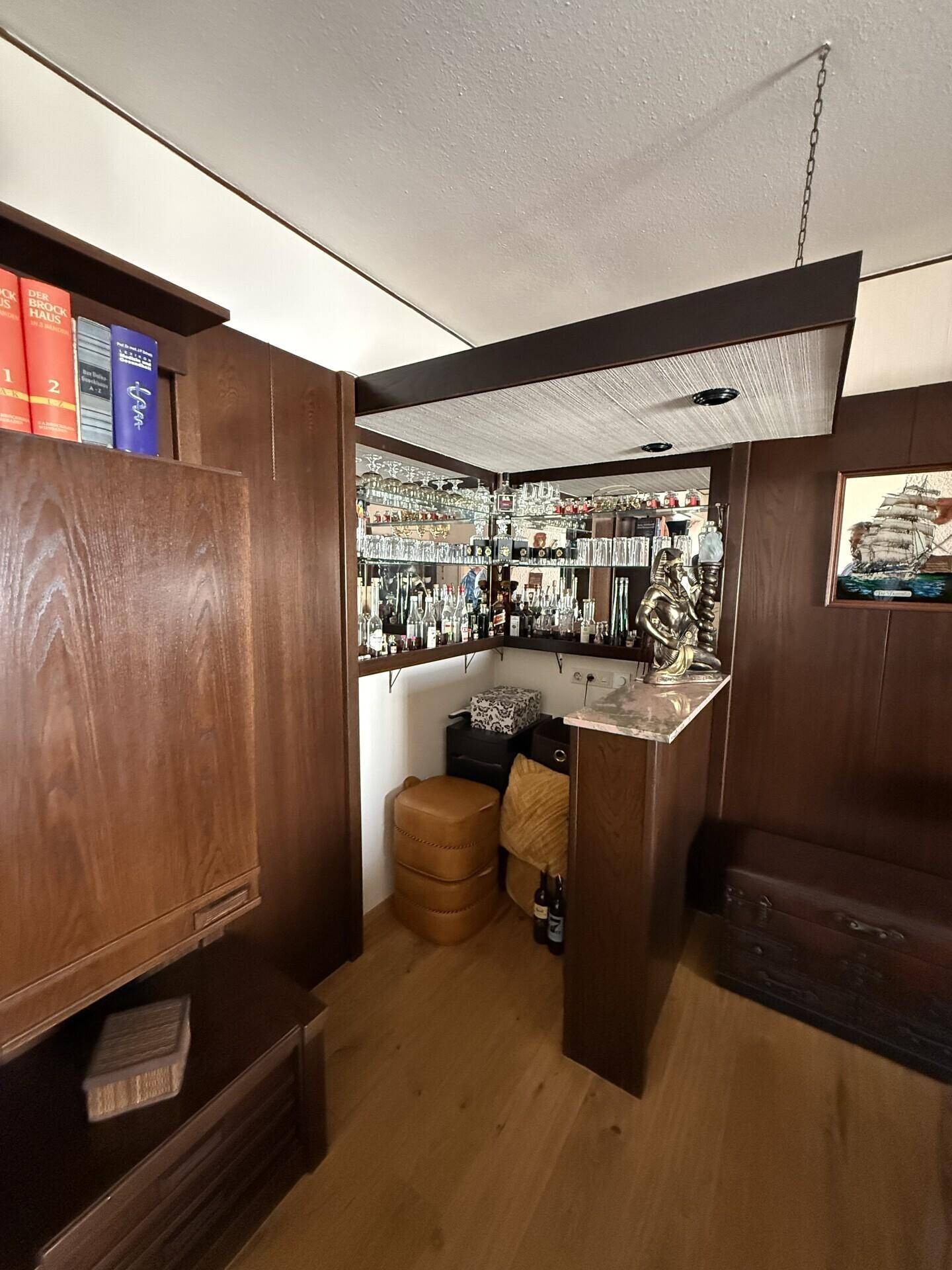 Gemütliche Hausbar mit Holzvertäfelung, Spiegeln und reichlich Gläsern.