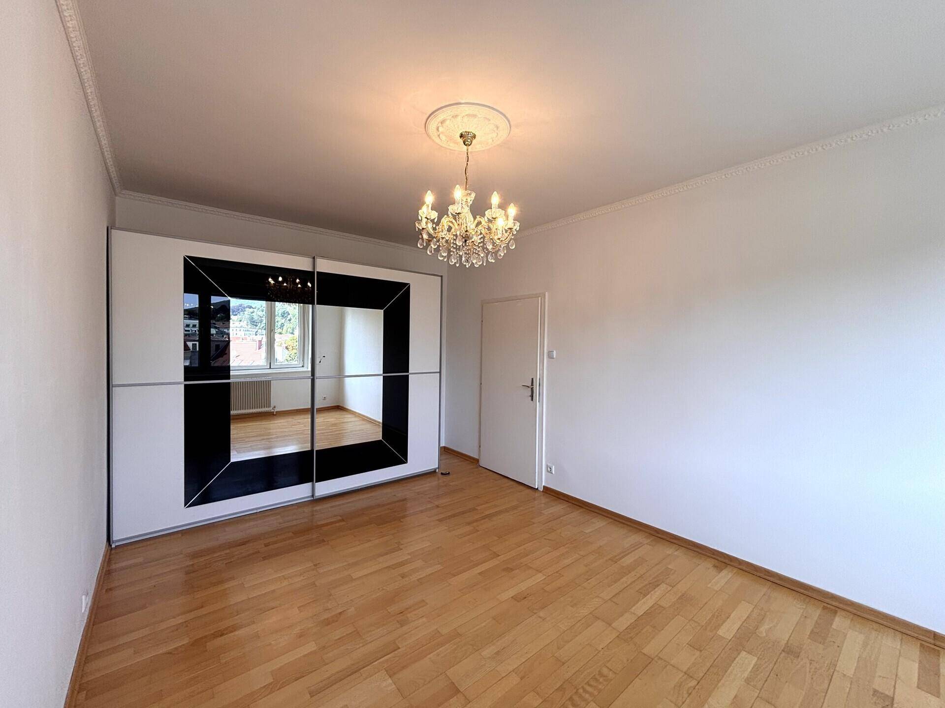 Schlafzimmer mit hellem Holzboden und großem Spiegelschrank, der den Raum optisch vergrößert.
