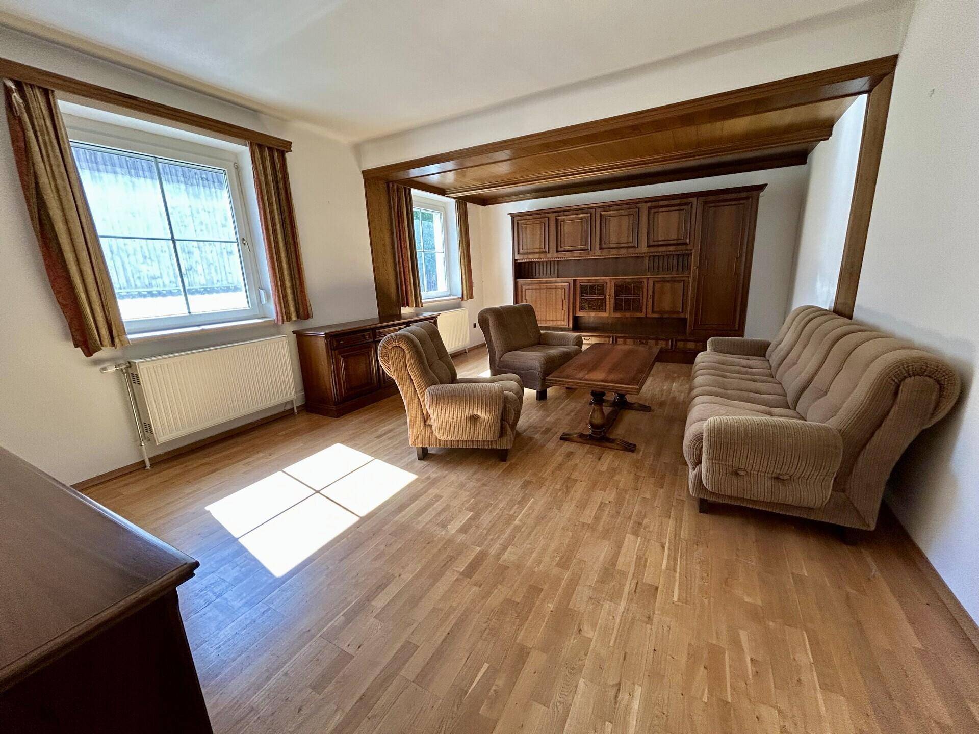 Gemütliches Wohnzimmer mit Parkettboden, Holzbalken und traditionellen Möbeln.