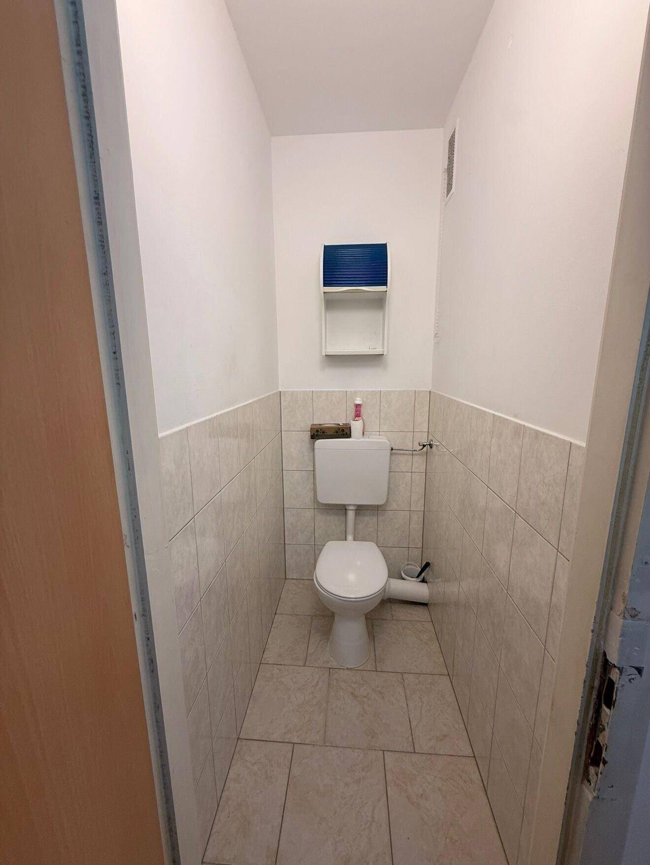 Funktionelles Gäste-WC mit hellen Fliesen an Boden und Wänden sowie einer Toilette.