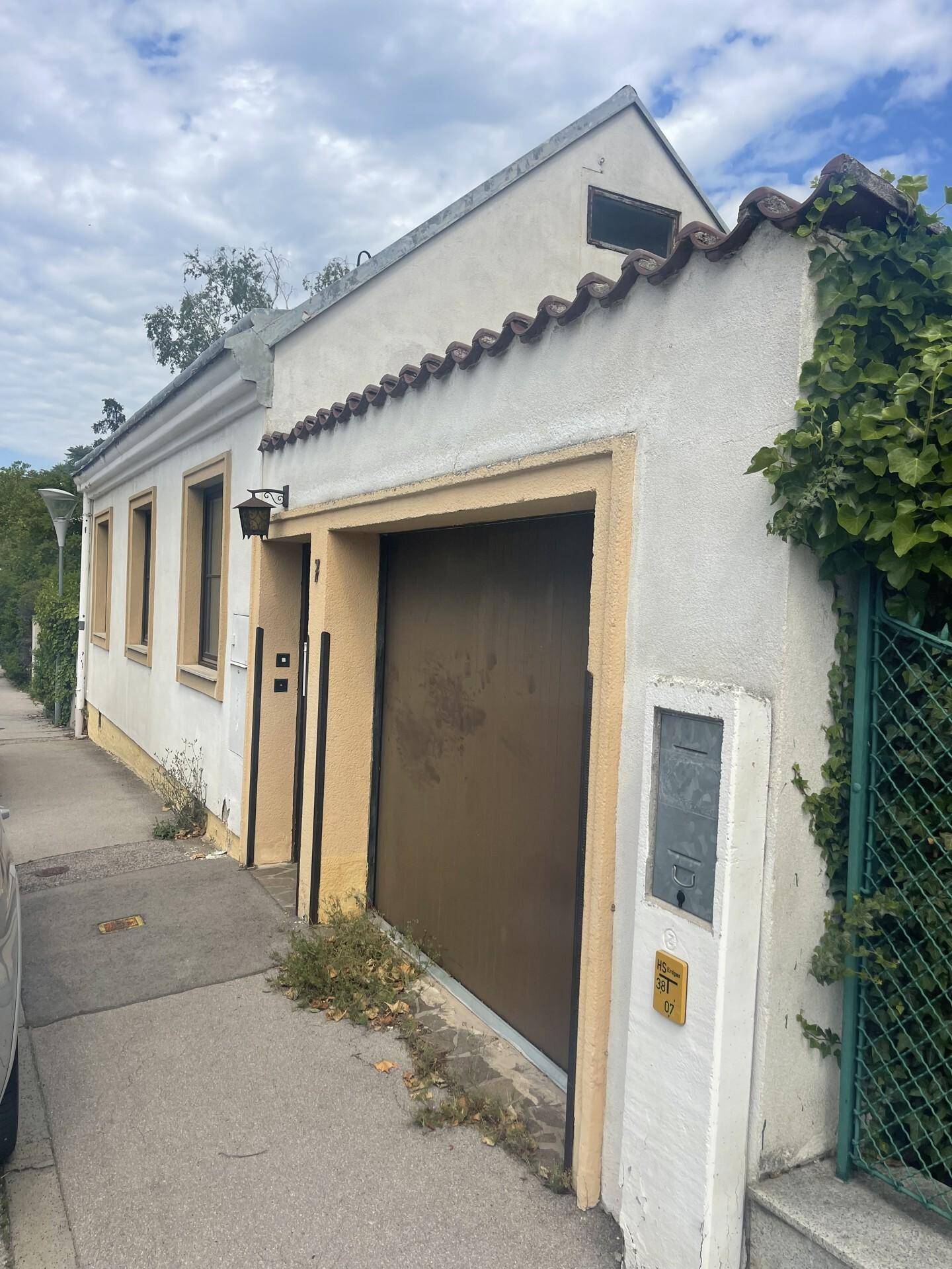 Vorderansicht des Hauses mit Garagentor und Efeu an der Fassade, von der Straße aus.