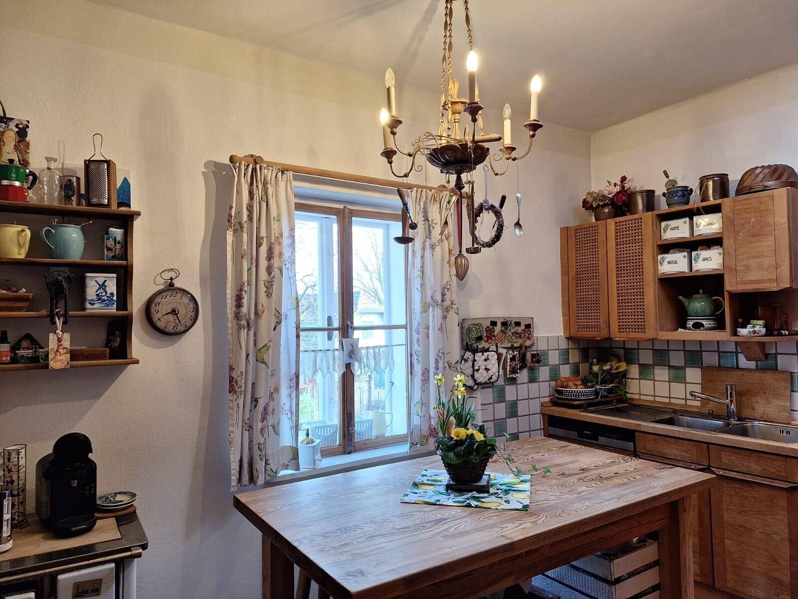 Rustikale Küche mit Holzschränken, Esstisch und traditionellem Kronleuchter.