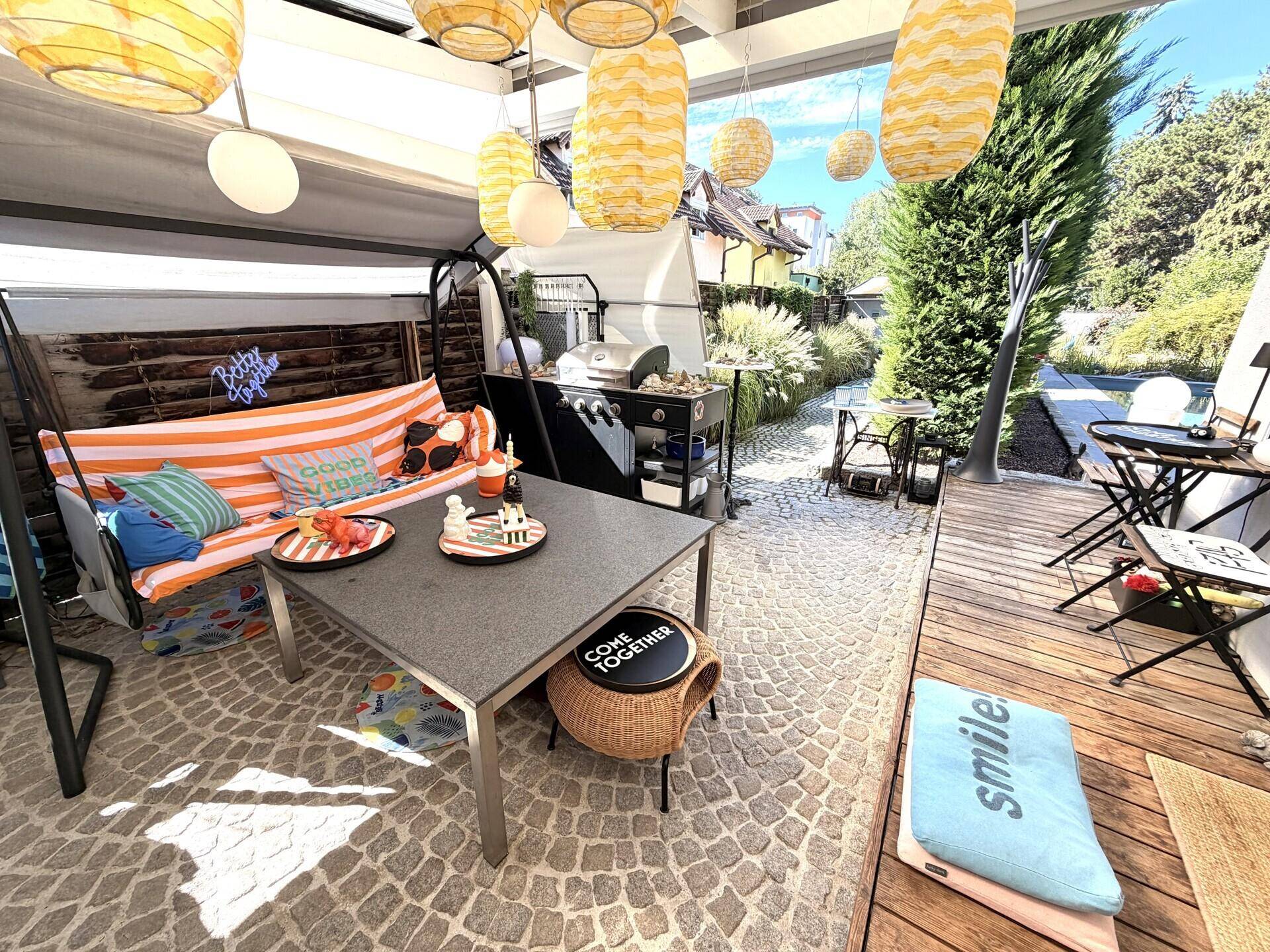 Überdachte Terrasse mit gemütlichen Sitzgelegenheiten und Grillbereich im Freien.