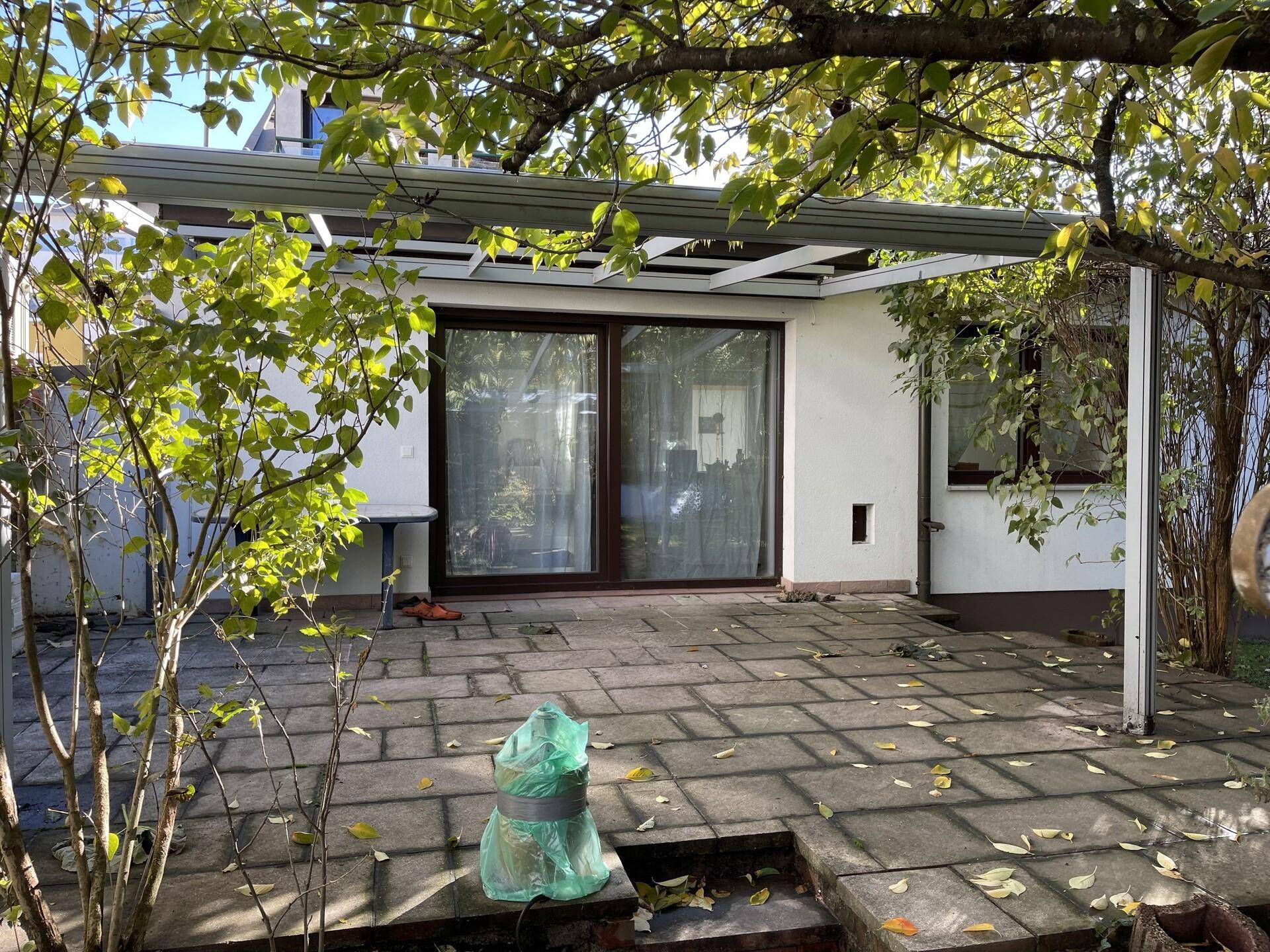 Gepflasterte Terrasse mit Überdachung und großen Schiebetüren zum Innenbereich.