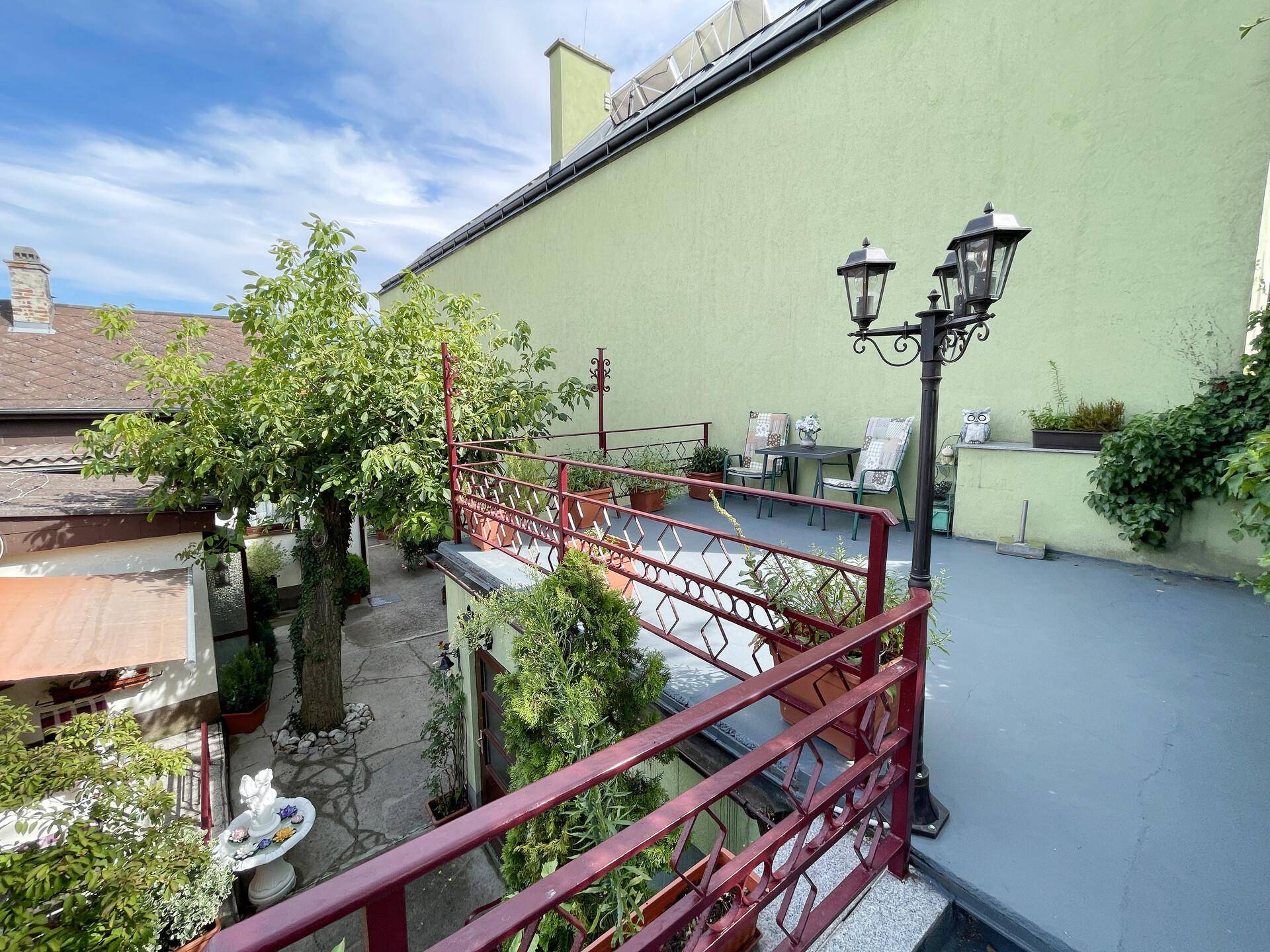 Erhöhte Terrasse mit Geländer, Außenleuchte und Blick auf die Umgebung.