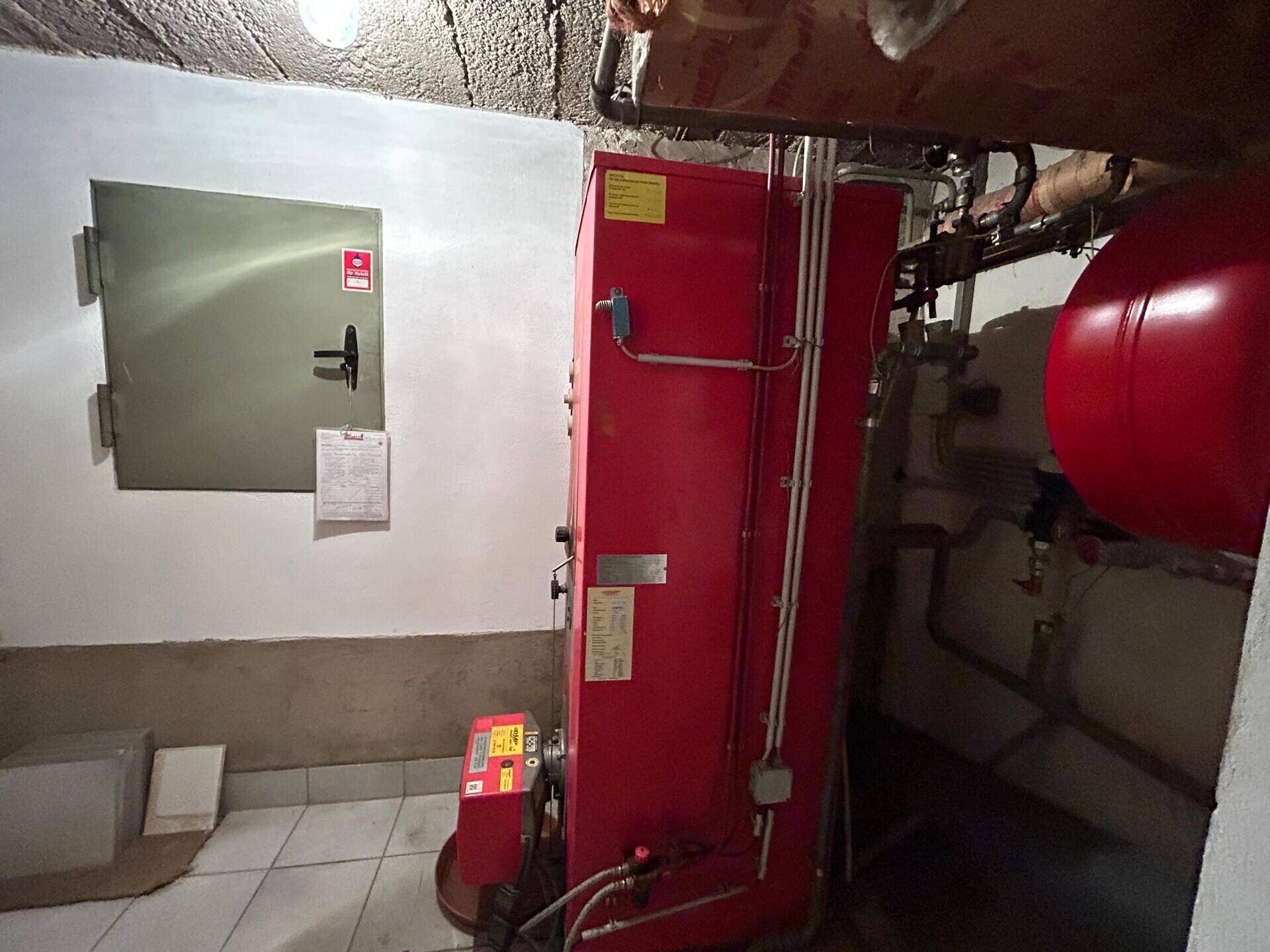 Heizungsraum im Keller mit großem Heizkessel und Warmwasserspeicher.