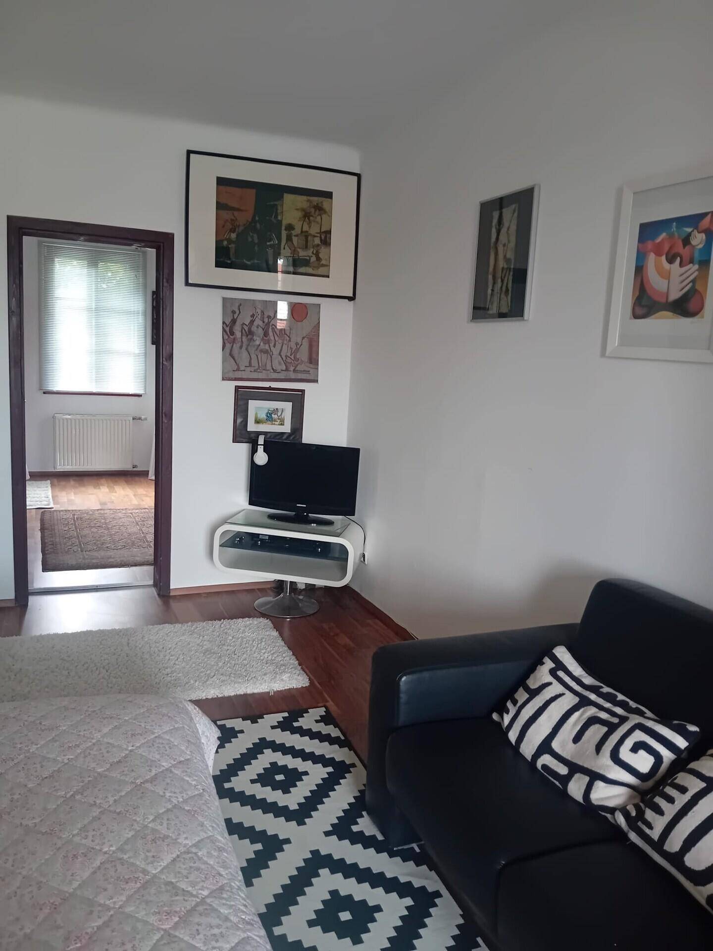 Gemütliches Schlafzimmer mit Bett, kleinem Sofa und Fernseher, Holzboden.