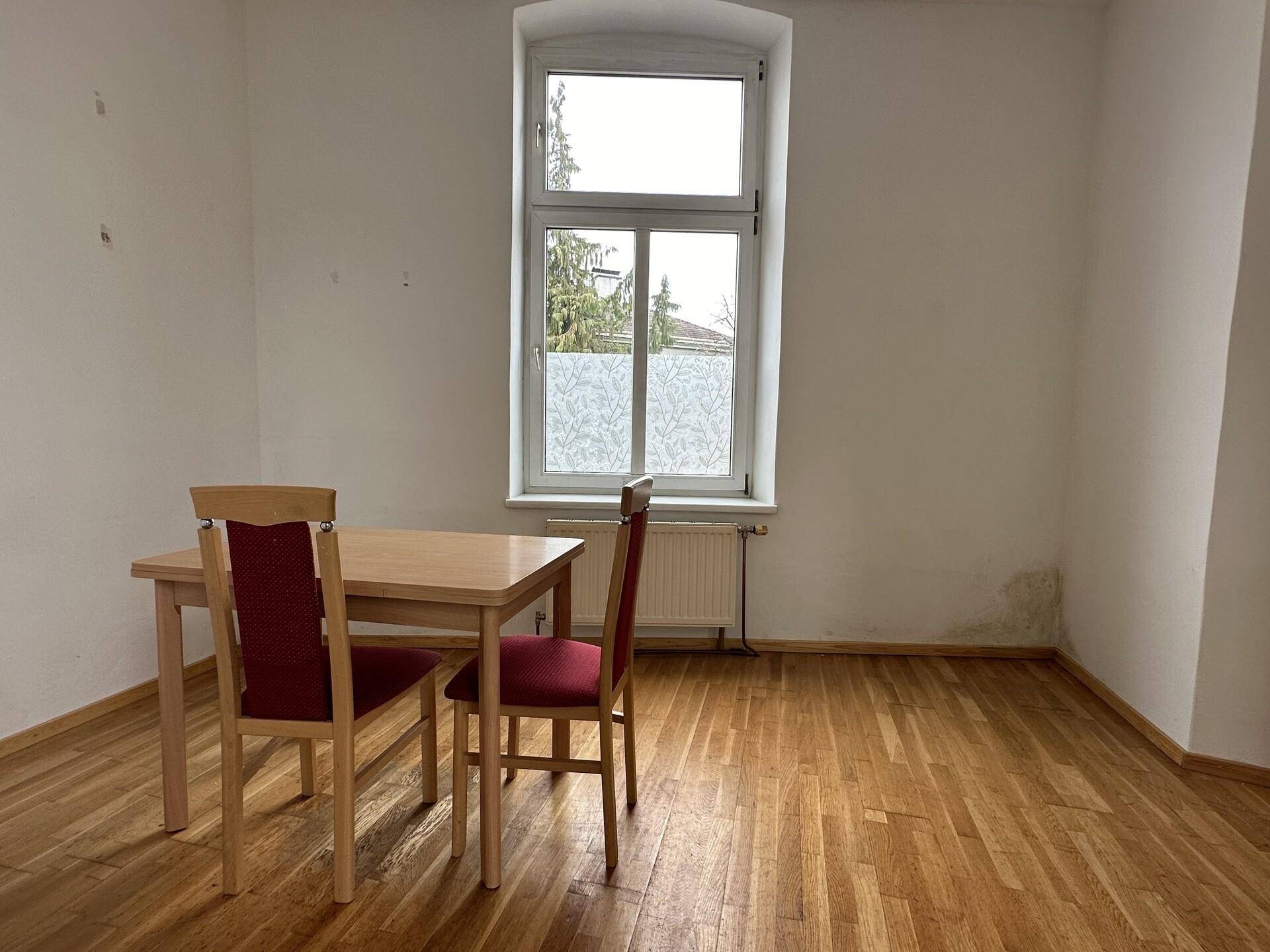 Gemütlicher Essbereich mit Holztisch und roten Stühlen, ideal für gemeinsame Mahlzeiten am Fenster.