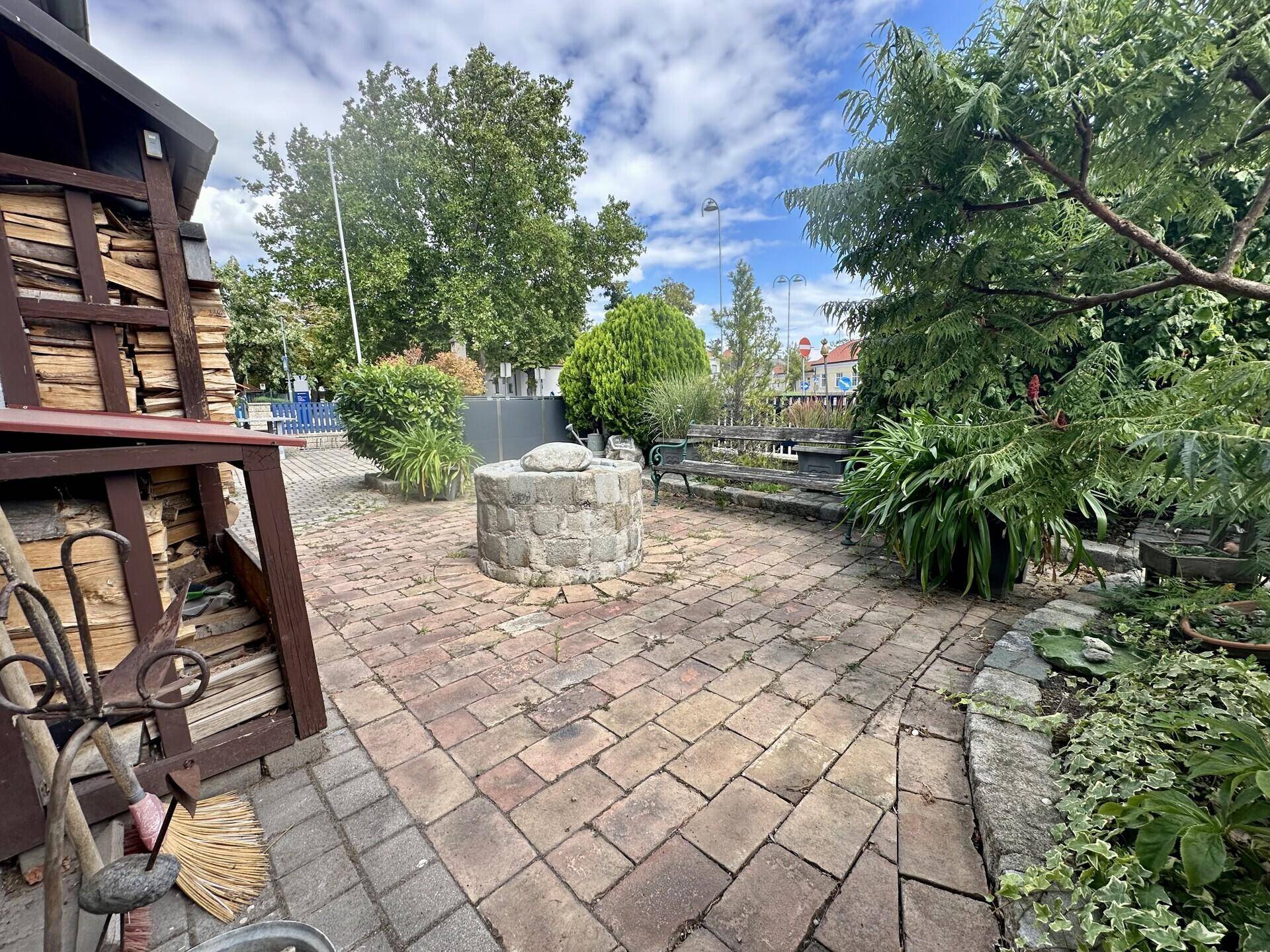 Weitläufige Terrasse mit Sitzgelegenheiten, Feuerstelle und üppiger Bepflanzung.