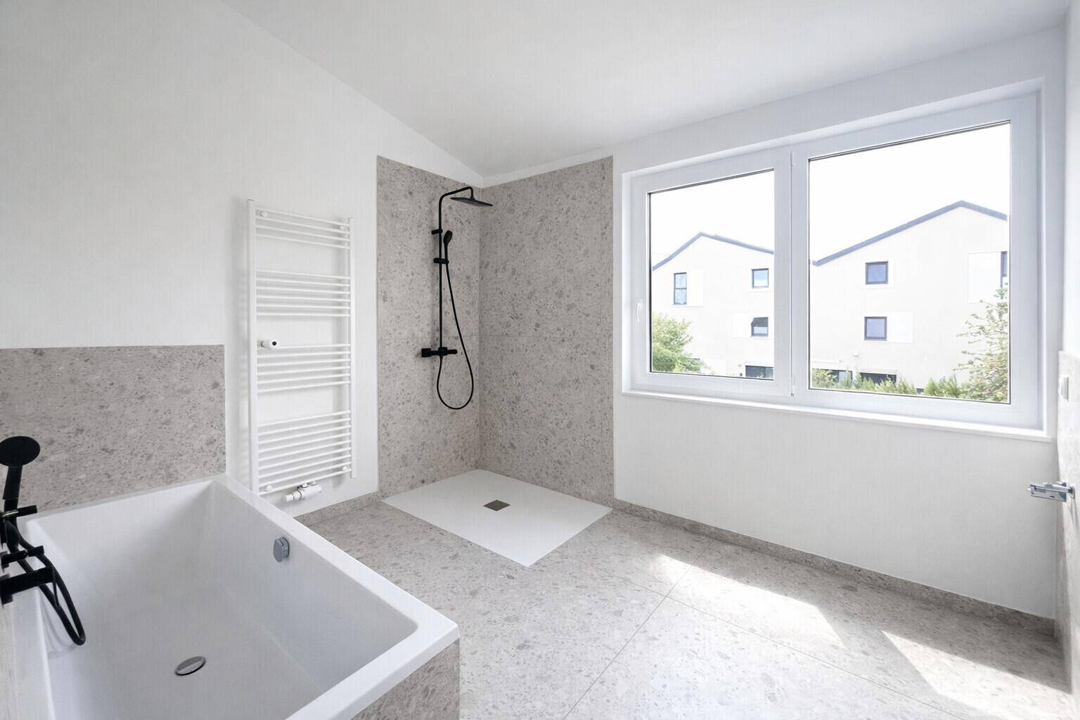 Modernes Badezimmer mit Badewanne, ebenerdiger Dusche, beheiztem Handtuchhalter und Fenster.