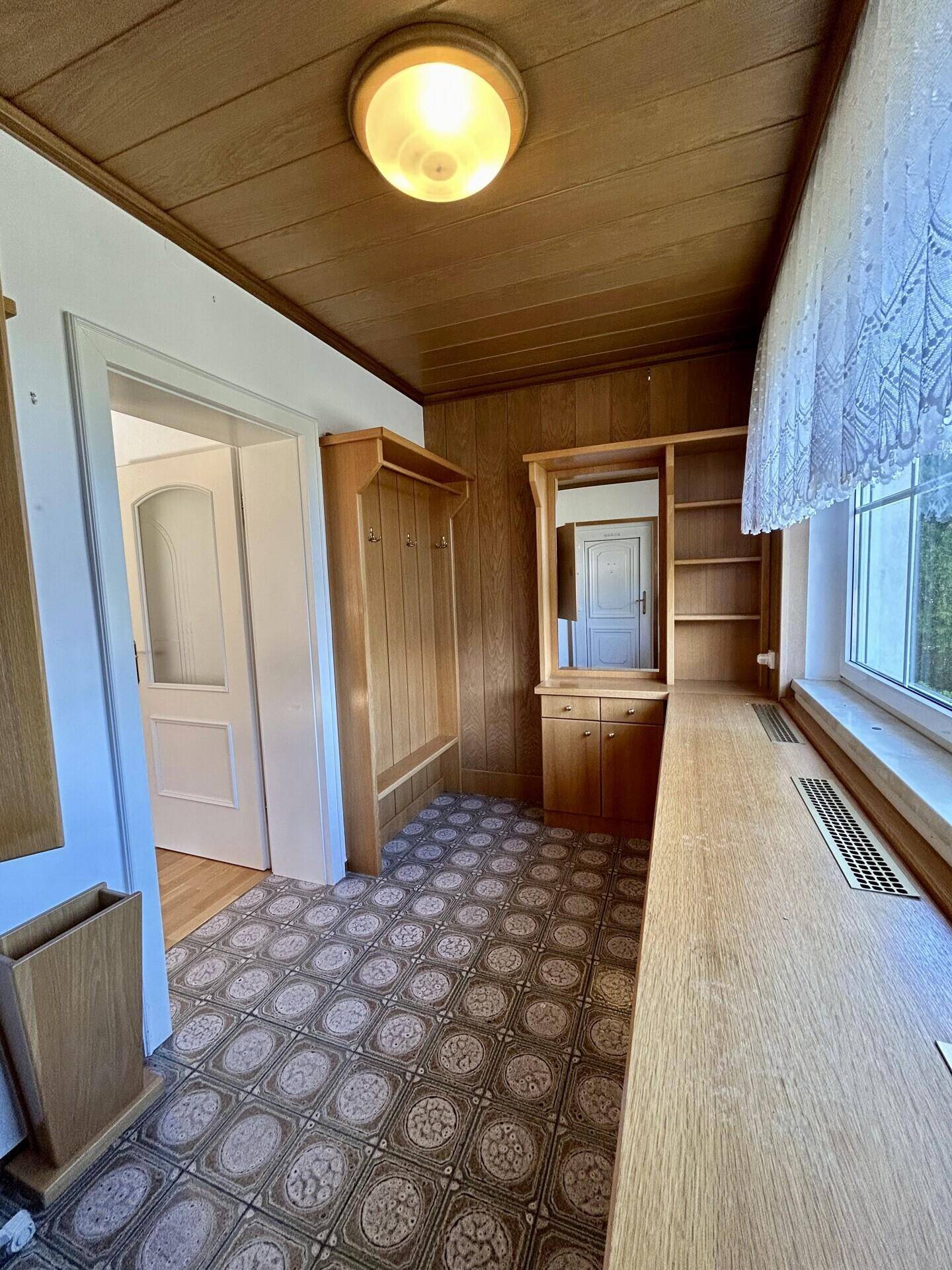 Heller Flur mit Holzdecke, gemustertem Boden und Garderobe.