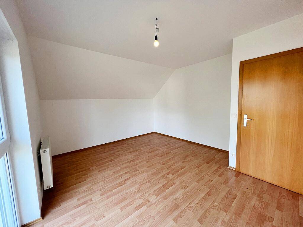 Ruhiges Schlafzimmer mit Laminatboden und Dachschräge, bereit zur individuellen Gestaltung.
