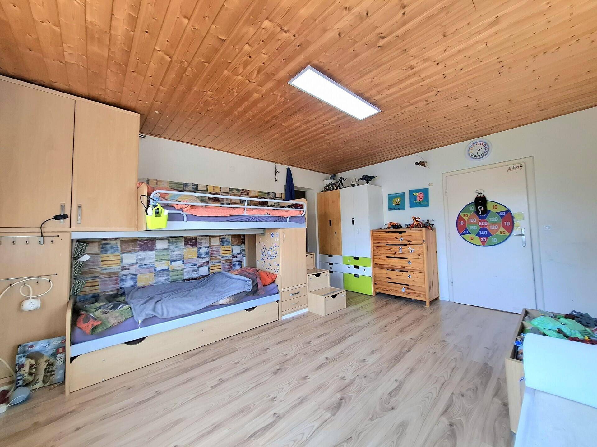 Kinderzimmer mit Etagenbett, Holzbalkendecke und viel Stauraum, ideal für Geschwister.