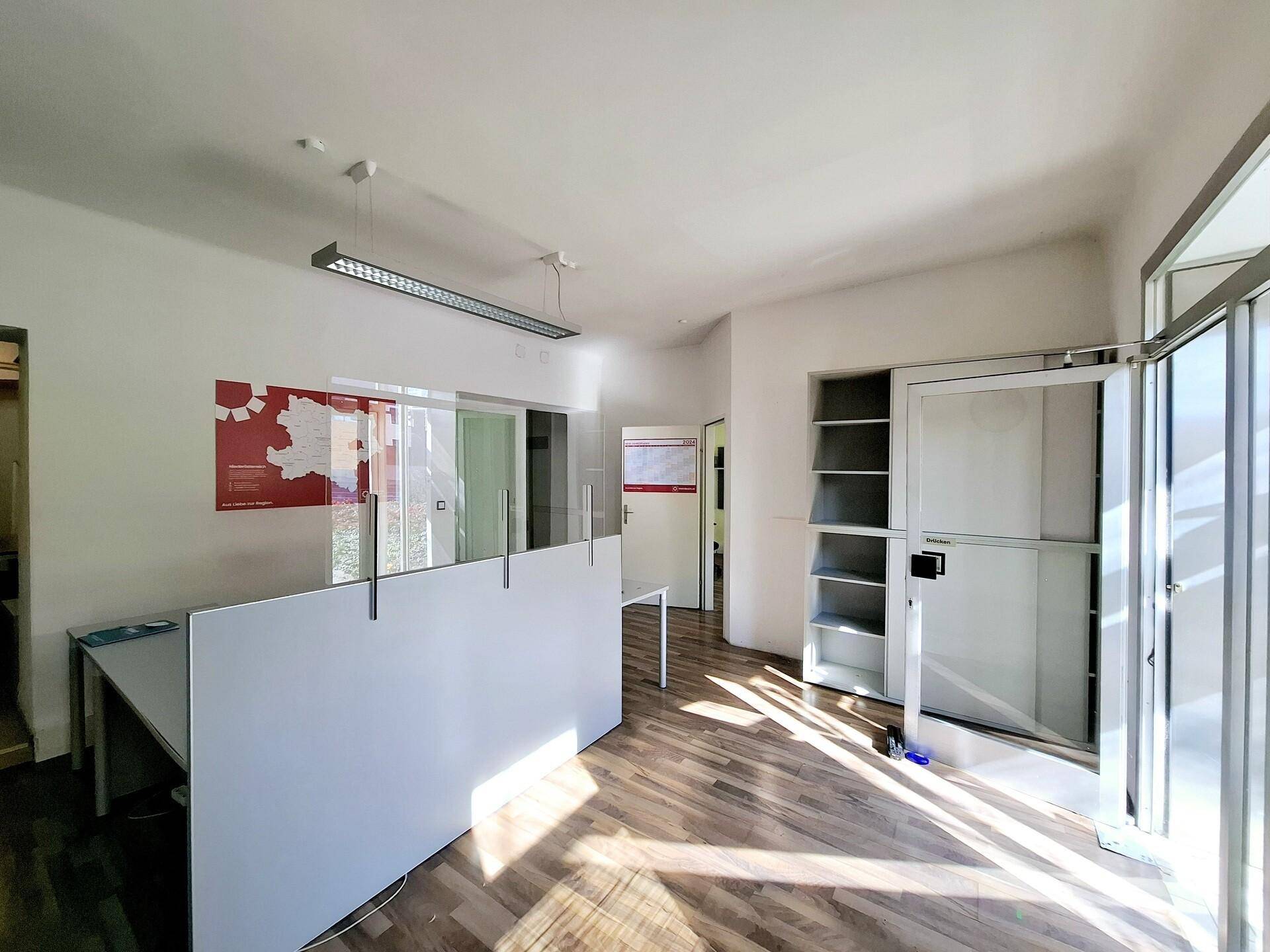 Helles Büro mit Holzboden, modernen Büromöbeln und viel Tageslicht durch große Fenster.