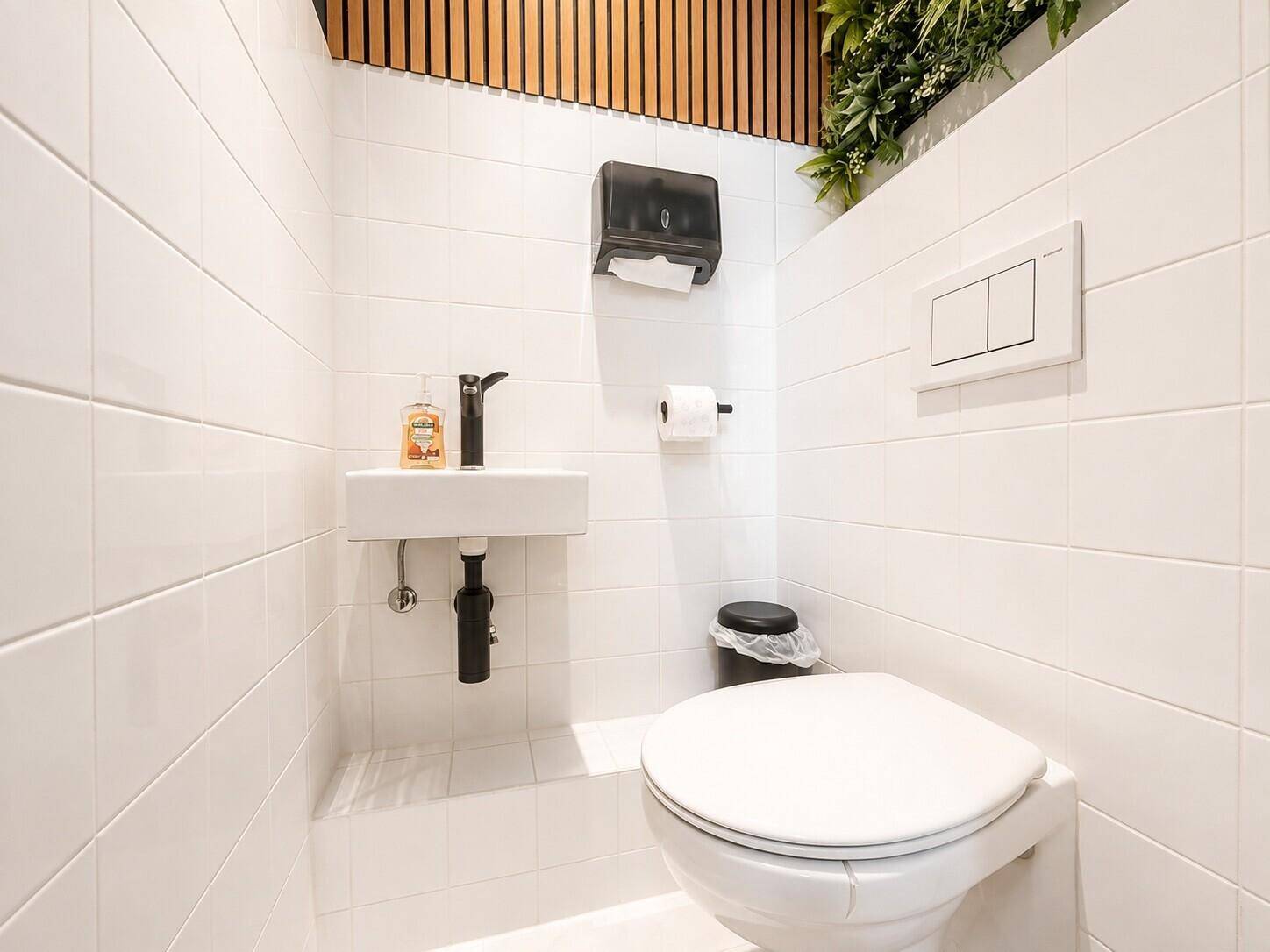 Kleines, modernes Gäste-WC mit weißen Fliesen, wandhängendem WC und minimalistischem Waschbecken.