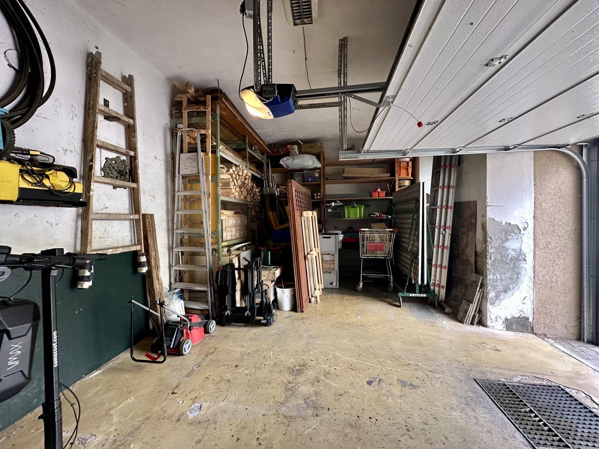 Innenansicht der Garage mit umfangreichen Lagerflächen und automatischem Torantrieb.